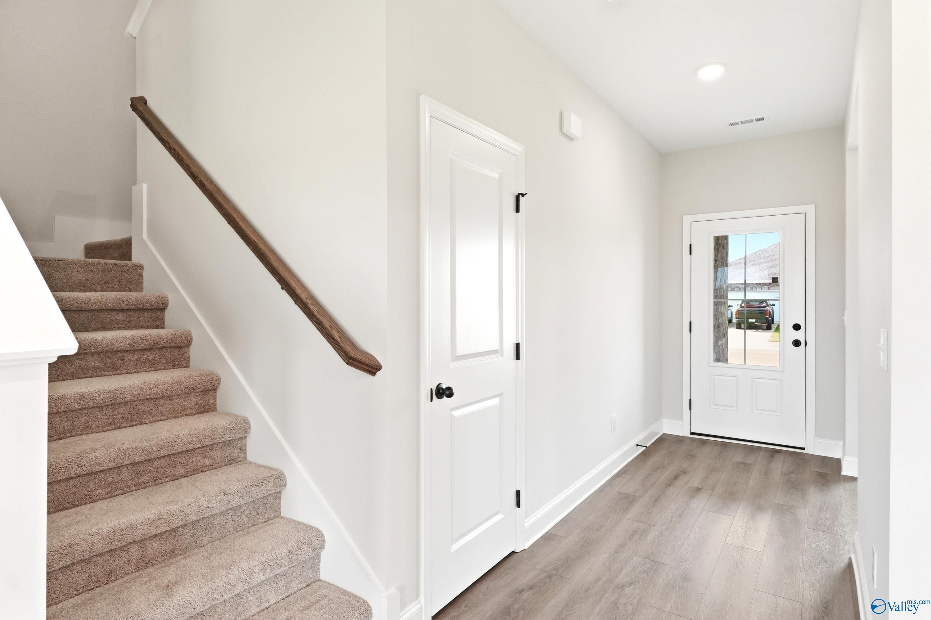Bright entryway with carpeted staircase and wood-style flooring in The Shelby A floor plan, Clearview, Hazel Green, AL.