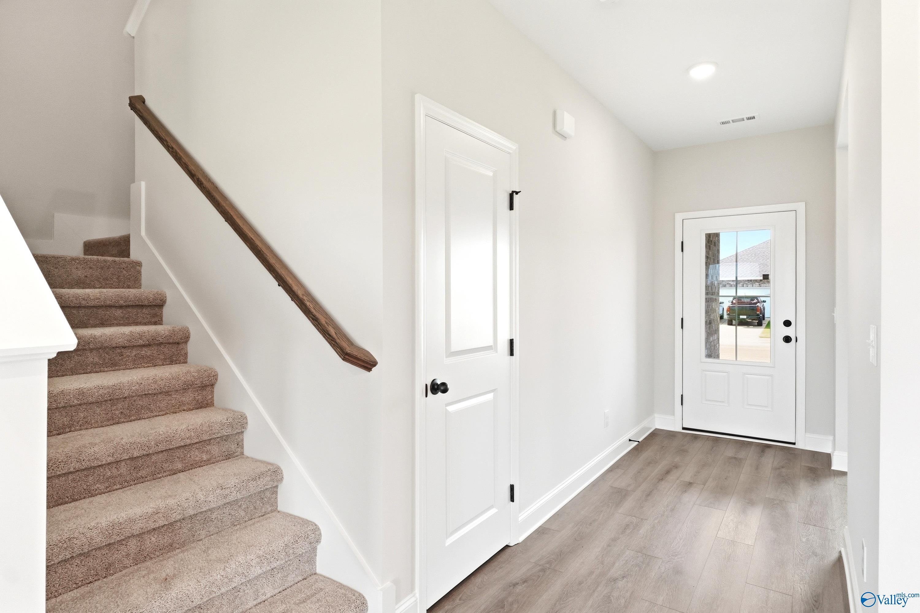 Bright entryway with carpeted staircase and wood-style flooring in The Shelby A floor plan, Clearview, Hazel Green, AL.