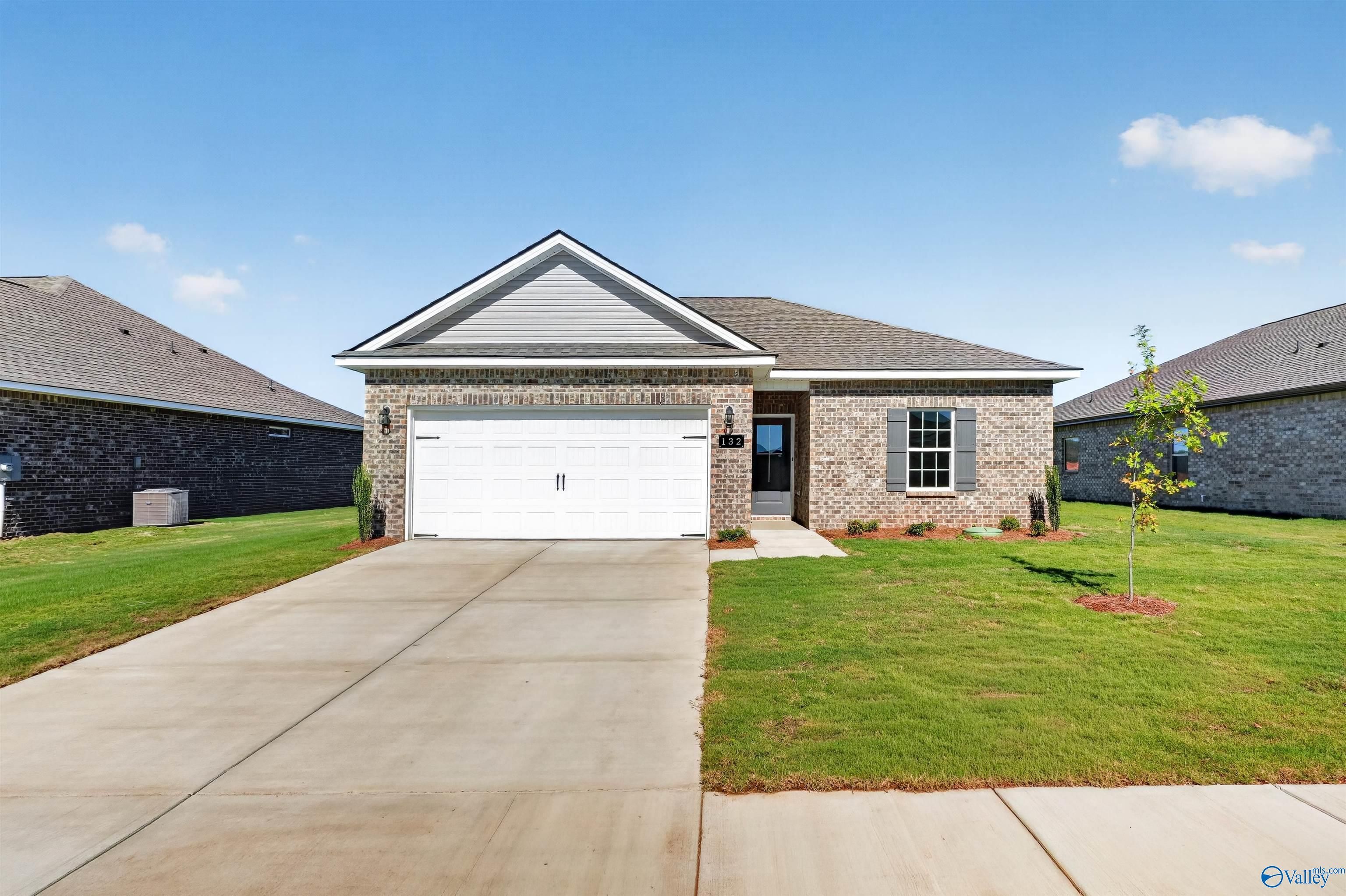 Brick front exterior with 2-car garage and landscaped yard at The Butler, a 3-bedroom Davidson Homes plan in Heritage Lakes, New Market, AL