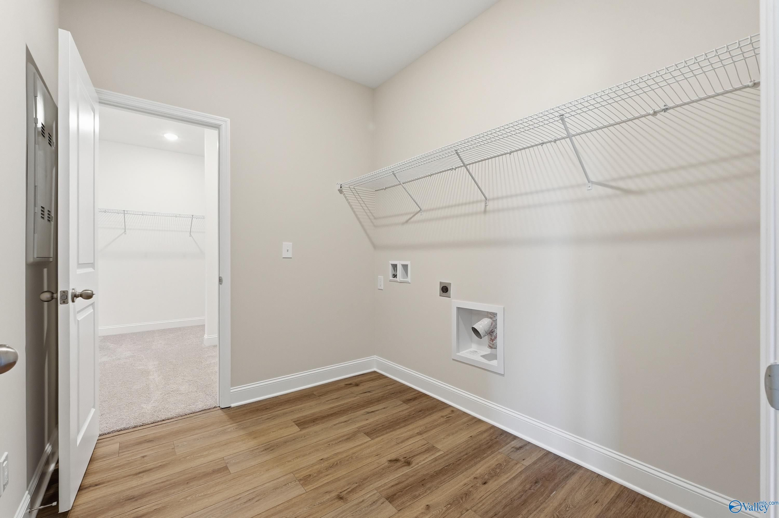 Spacious laundry room with wire shelving, washer dryer hookups, and hardwood floors in Davidson Homes The Everett, Harvest AL