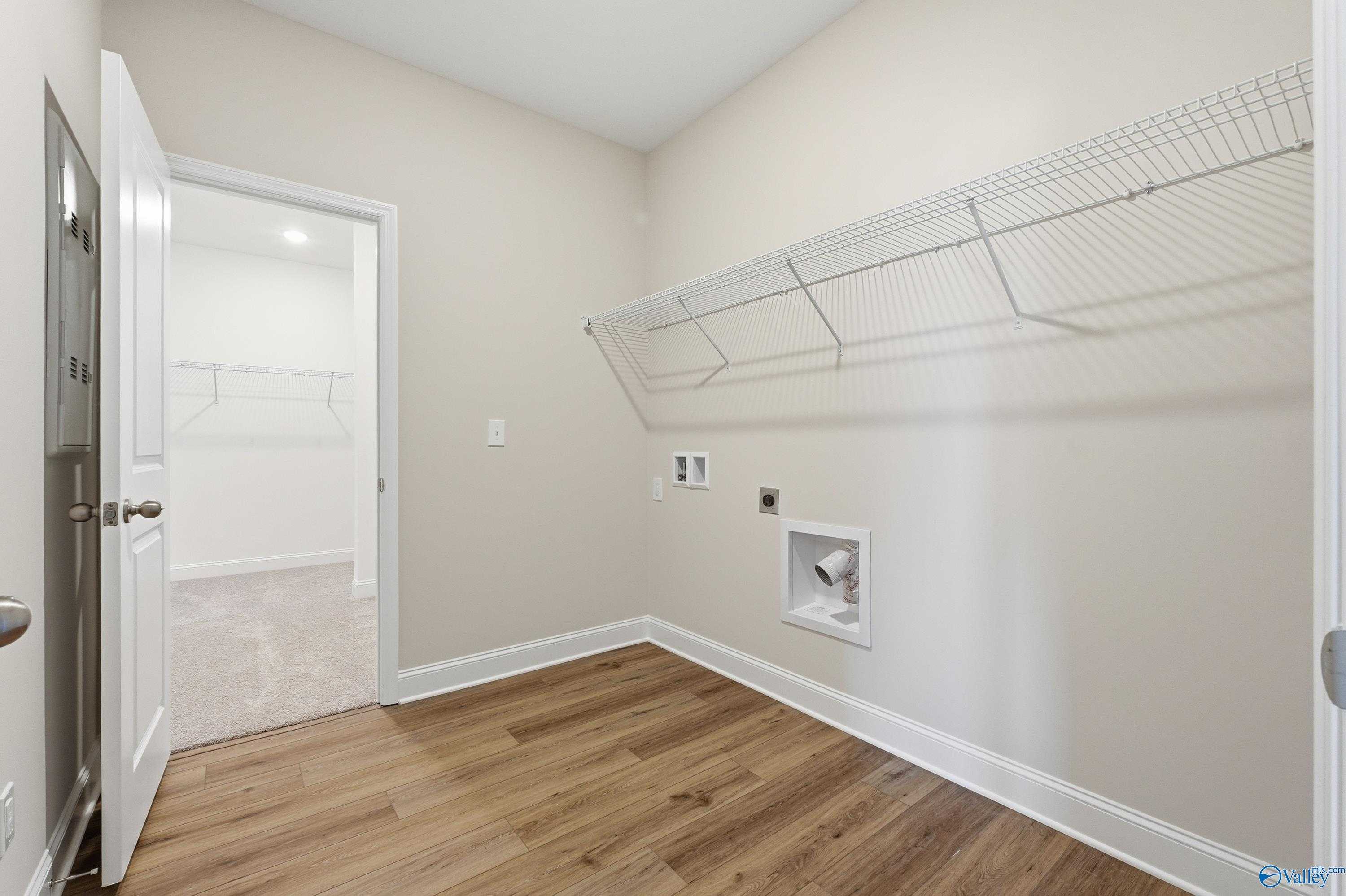 Spacious laundry room with wire shelving, washer dryer hookups, and hardwood floors in Davidson Homes The Everett, Harvest AL