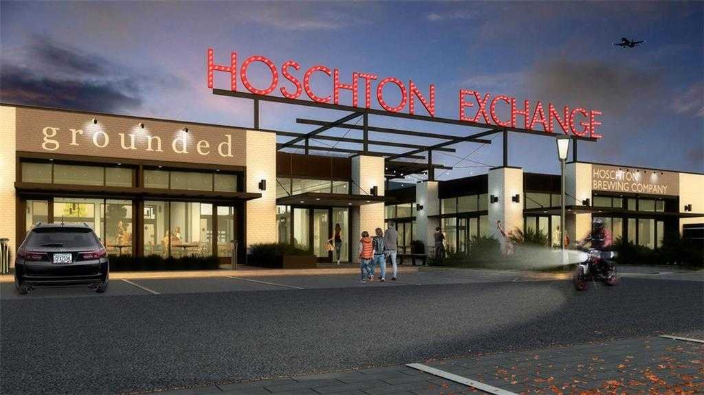 Vibrant Hoschton Exchange shopping center at dusk with Grounded cafe, Wedding Co. store, families walking in Hoschton, Georgia