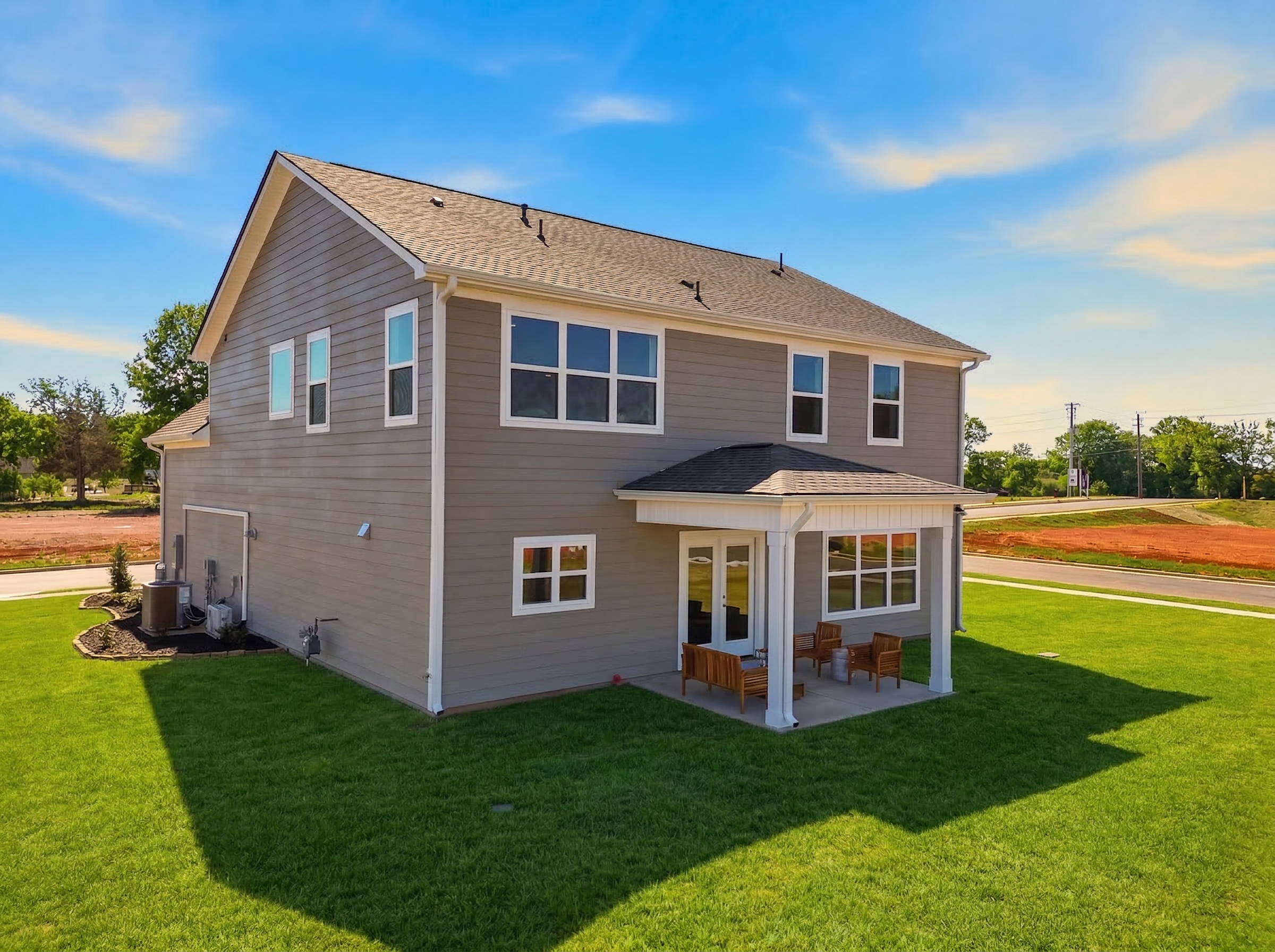 Two-story gray home exterior at Berry Cove in New Market Alabama with covered side porch, patio chairs, and green lawn