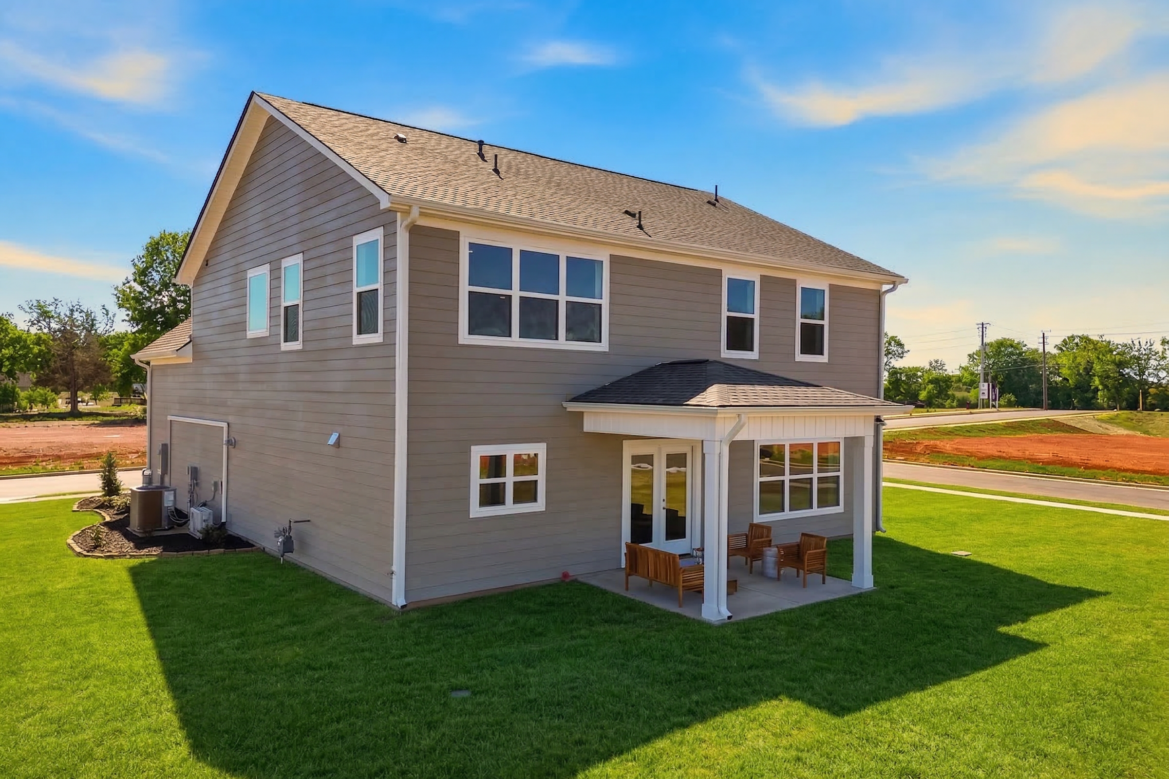 Two-story gray home exterior at Berry Cove in New Market Alabama with covered side porch, patio chairs, and green lawn