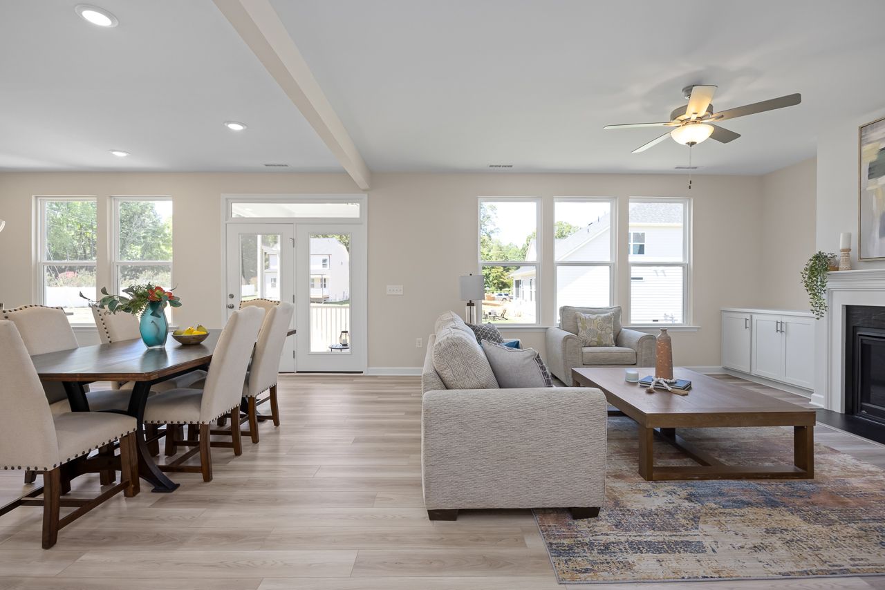 Open-concept living and dining area in The Chestnut featuring a modern fireplace, wood flooring, and bright natural light.
