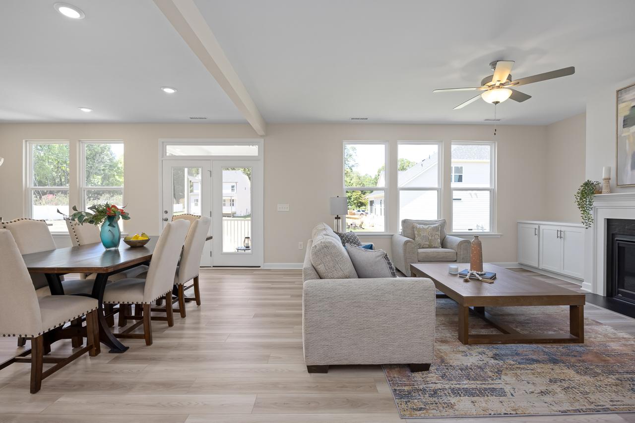 Open-concept living and dining area in The Chestnut featuring a modern fireplace, wood flooring, and bright natural light.
