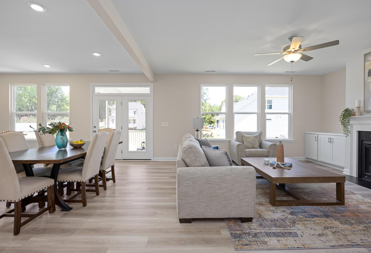 Open-concept living and dining area in The Chestnut featuring a modern fireplace, wood flooring, and bright natural light.