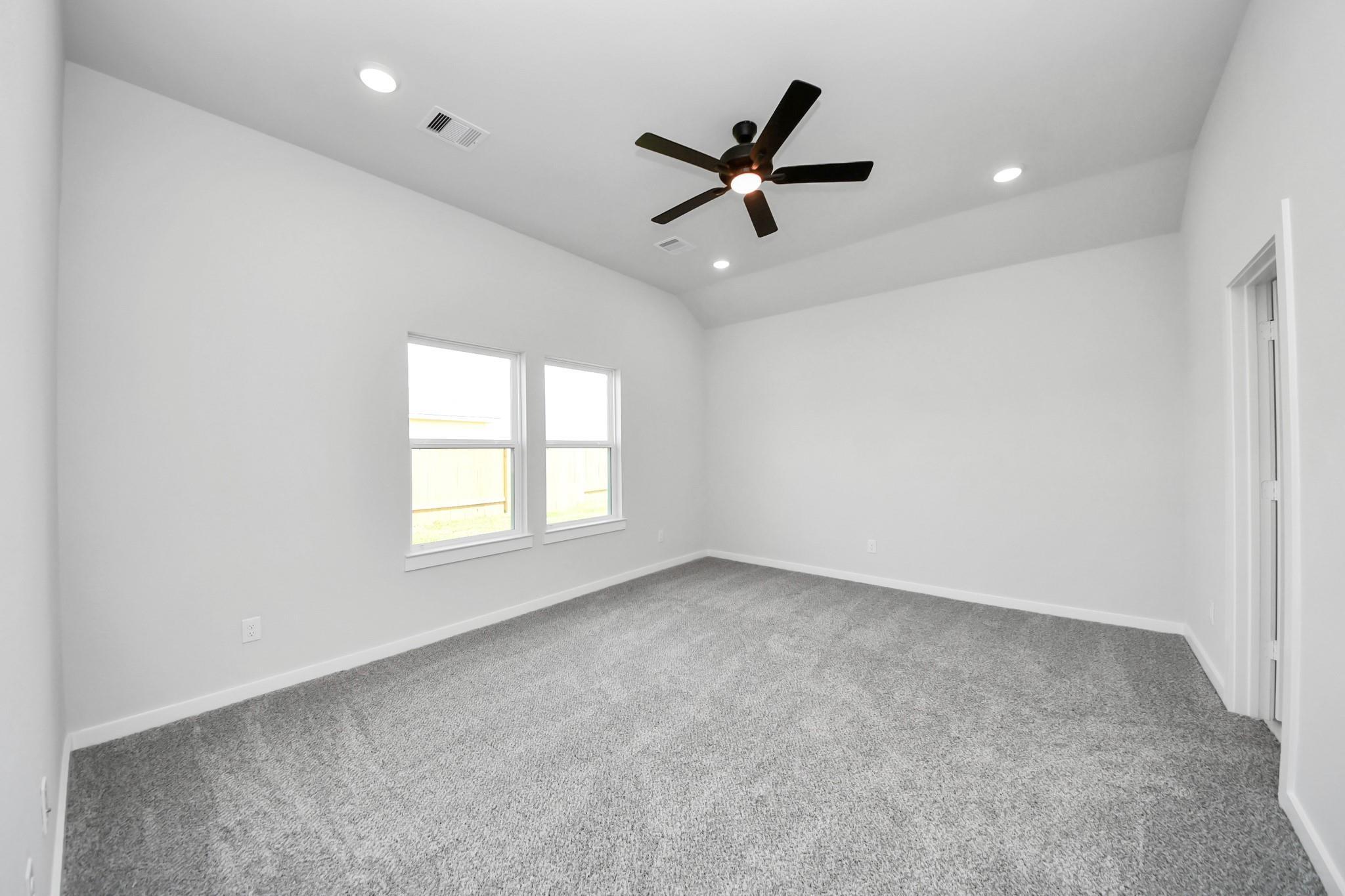 Spacious bedroom with vaulted ceilings, recessed lighting, and ceiling fan in The Riviera C home at River Ranch Meadows.