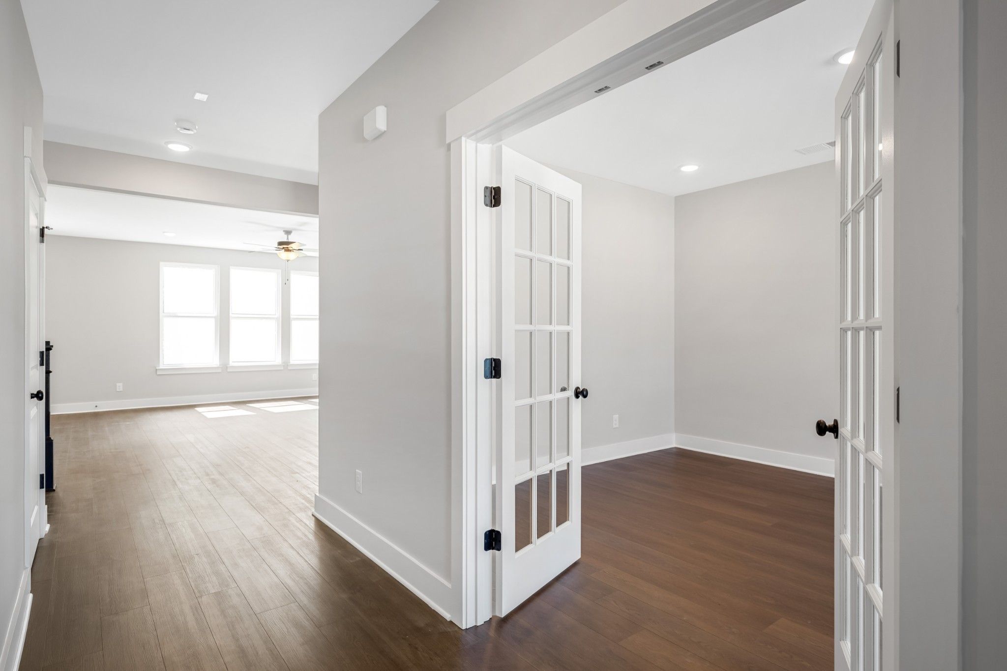 Bright hallway with hardwood floors and open white French doors to den in Davidson Homes The Henry C, Calista Farms, White House, TN