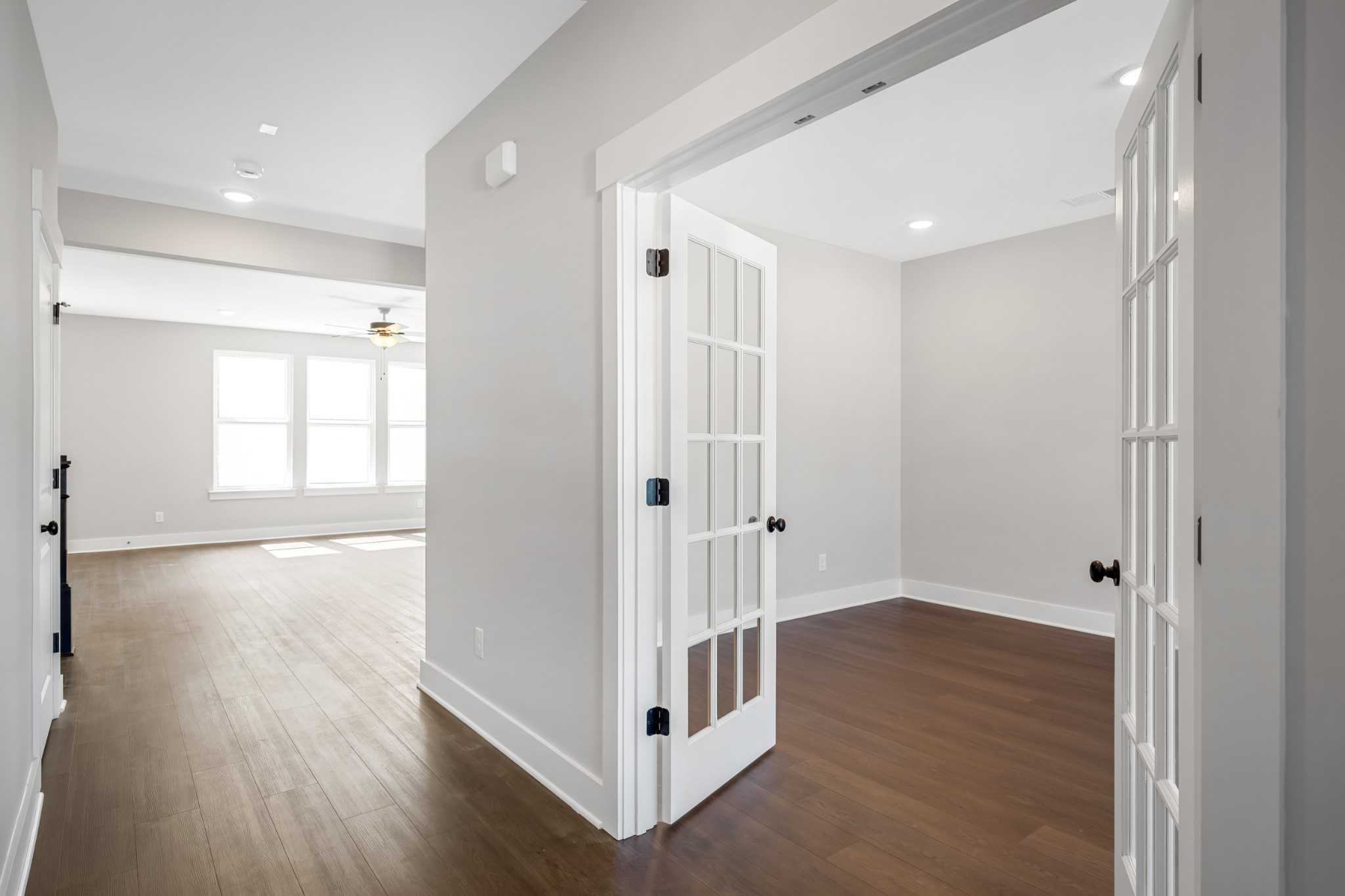 Bright hallway with hardwood floors and open white French doors to den in Davidson Homes The Henry C, Calista Farms, White House, TN