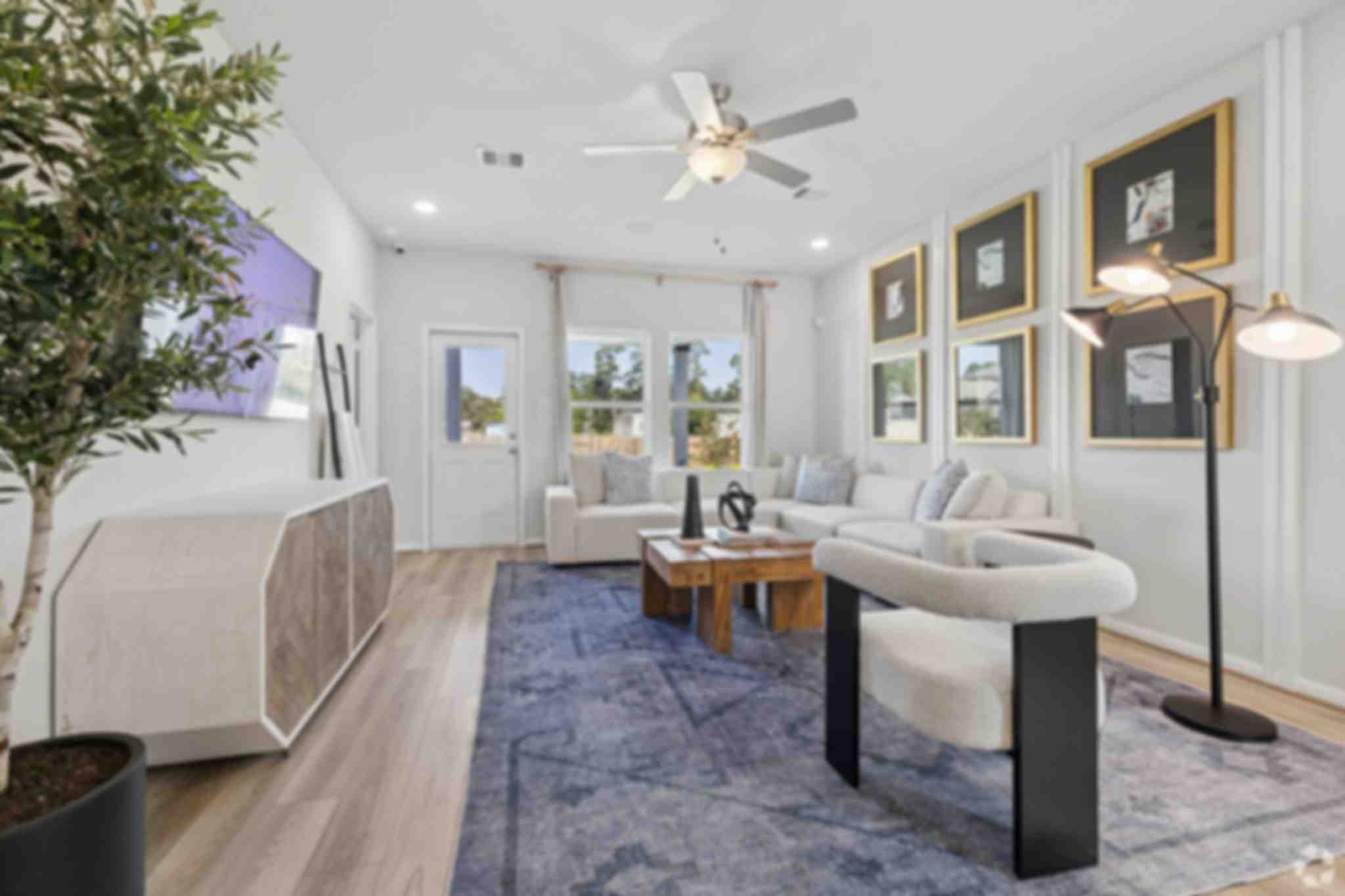 Spacious open-concept living and dining room at Liberty Estates in Cleveland Texas with white sectional sofa, wooden coffee table, and ceiling fan