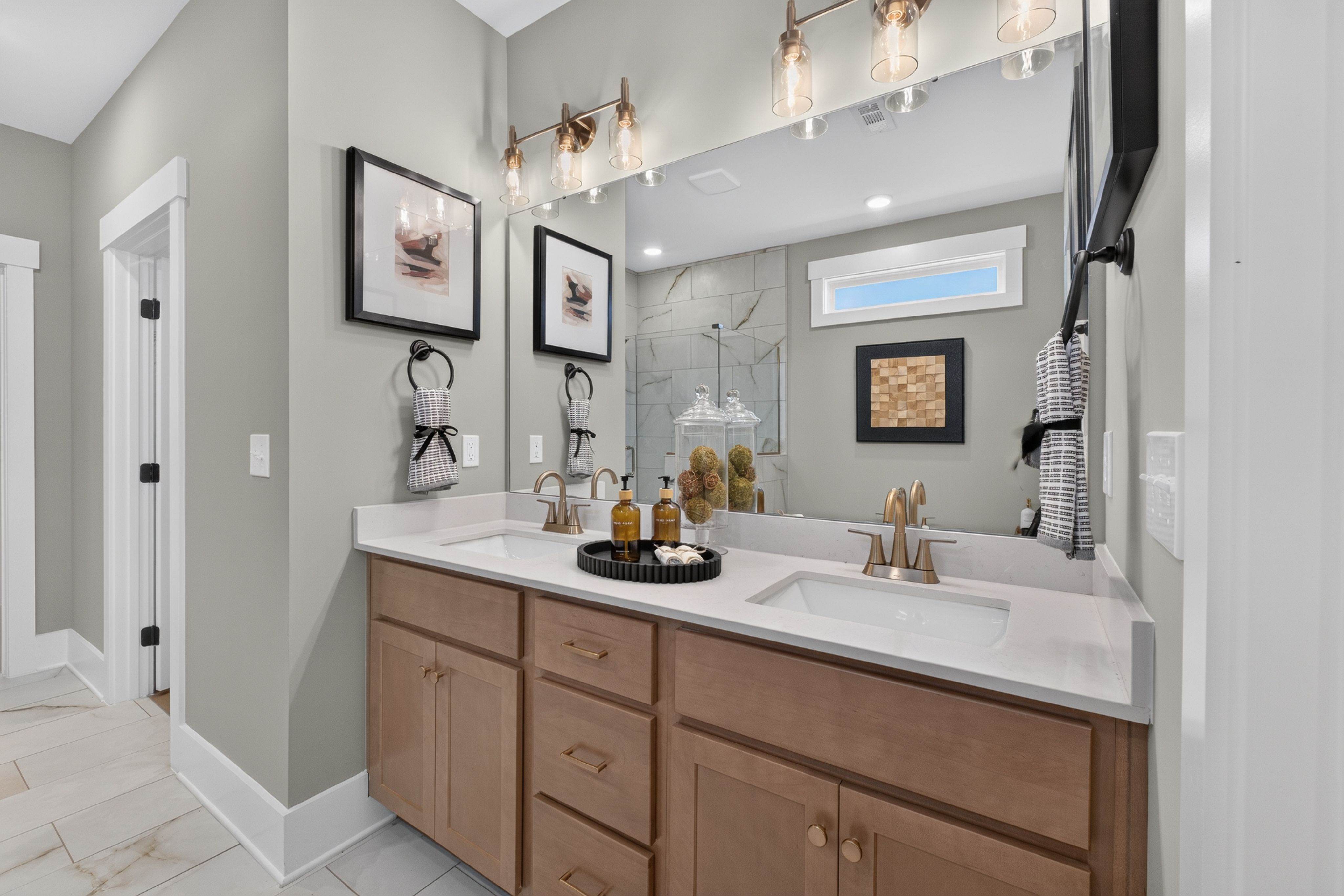 Dual vanity bathroom with wood cabinets and quartz countertops at Evergreen Mill by Davidson Homes in Madison, Alabama