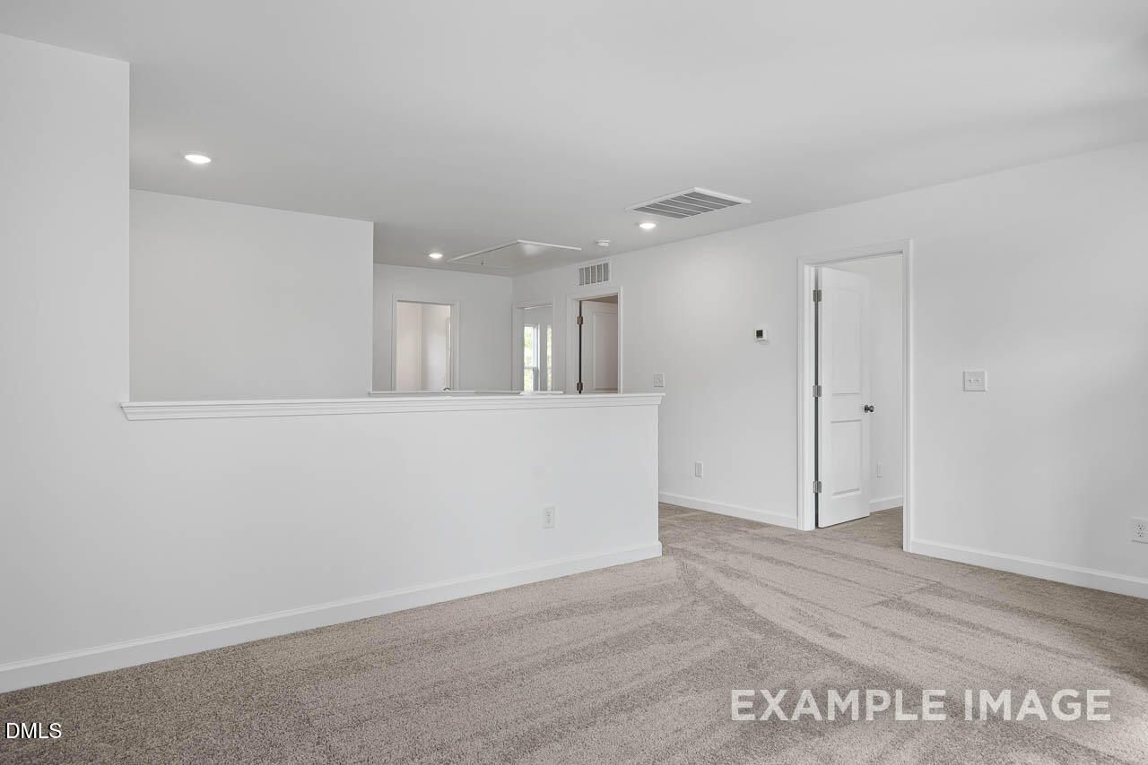 Spacious upstairs hallway with beige carpet, white railing overlook in Davidson Homes The Willow D, Zebulon, NC