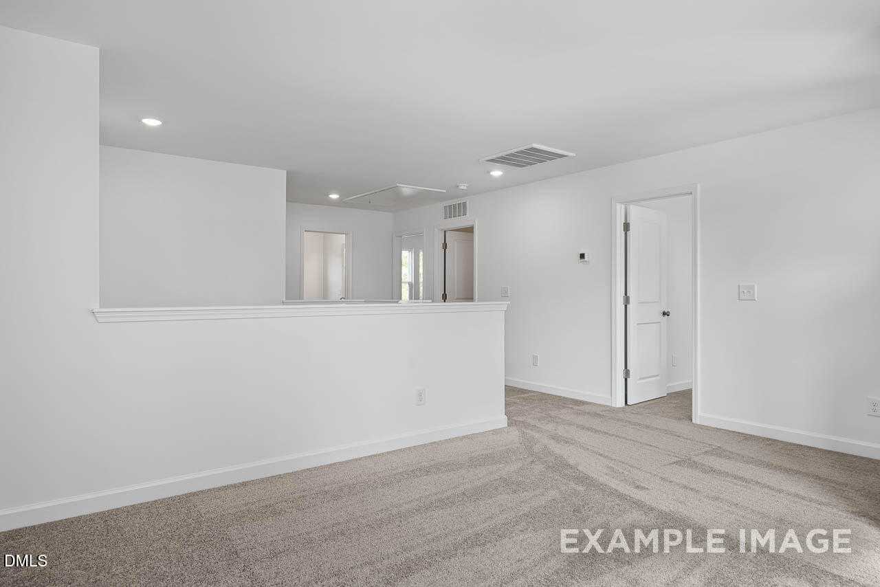 Spacious upstairs hallway with beige carpet, white railing overlook in Davidson Homes The Willow D, Zebulon, NC