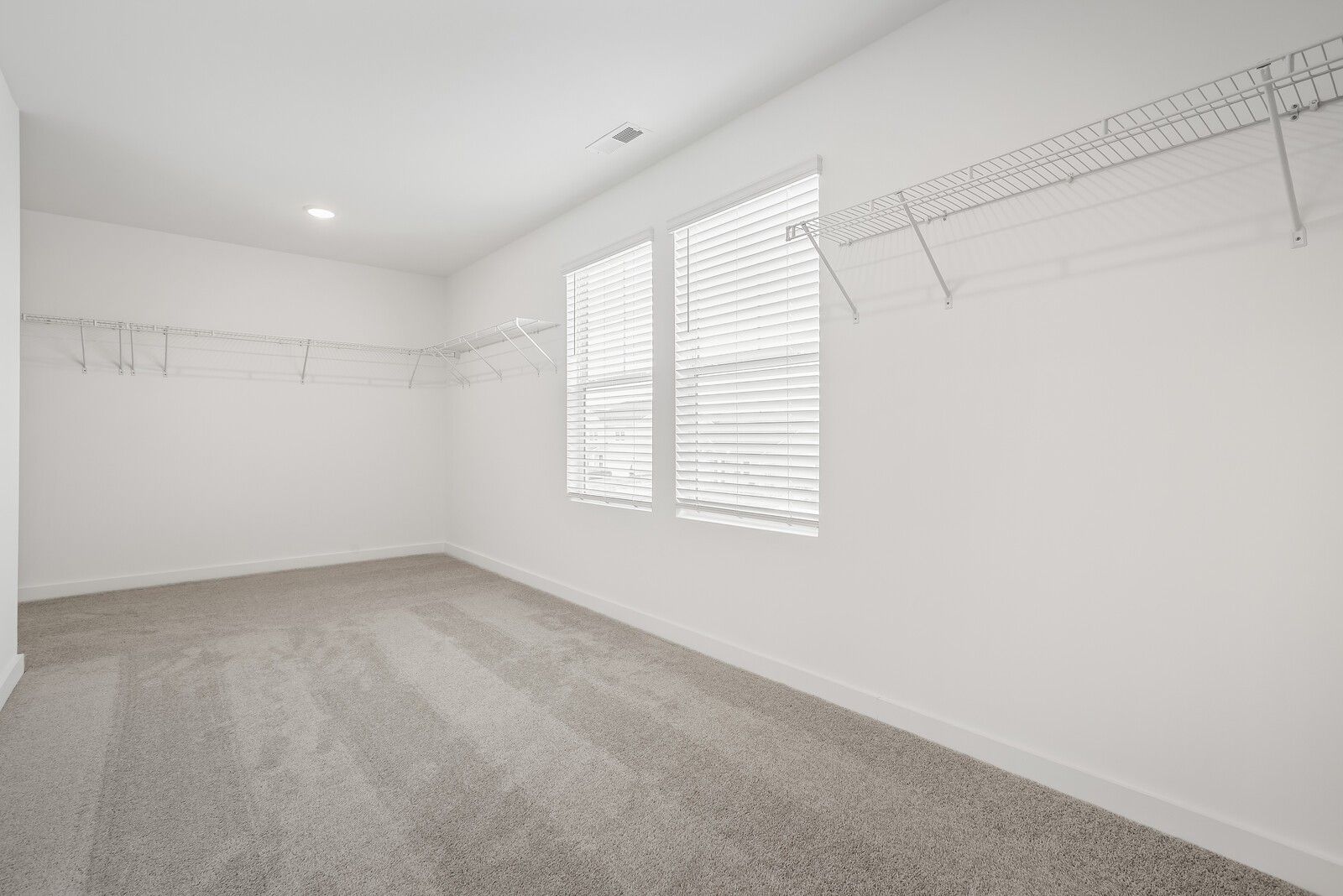 Spacious walk-in closet with white wire shelving, carpet flooring, and double windows with blinds in Davidson Homes The Gordon C, White House, TN