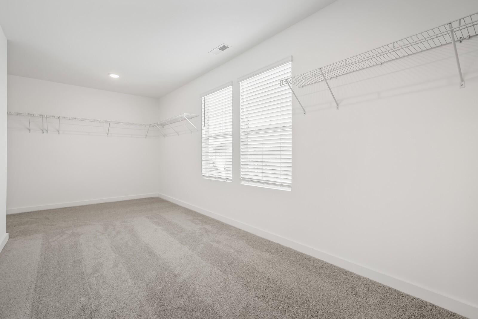 Spacious walk-in closet with white wire shelving, carpet flooring, and double windows with blinds in Davidson Homes The Gordon C, White House, TN