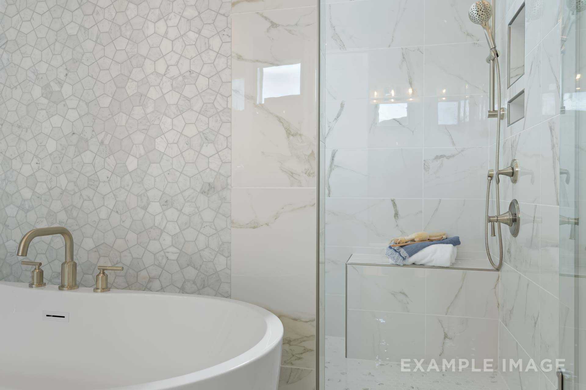 Spacious master bathroom in The Seaside A featuring freestanding tub, glass shower with marble walls, and hexagonal tile accents