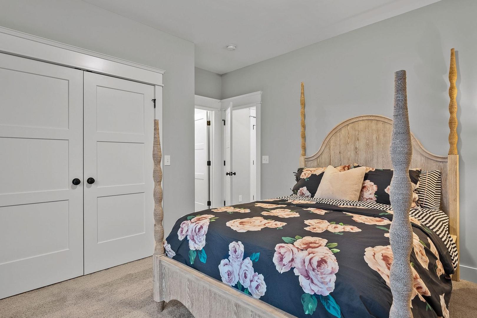 Spacious master bedroom in The Oxford featuring rustic four-poster bed with floral duvet and double closet doors
