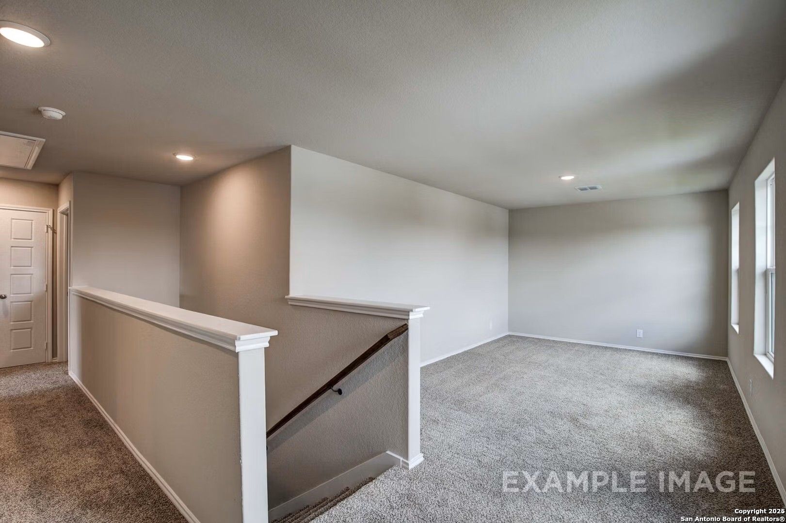 Bright upstairs hallway with staircase overlook and beige walls in Davidson Homes The Murray K, Comanche Ridge, San Antonio