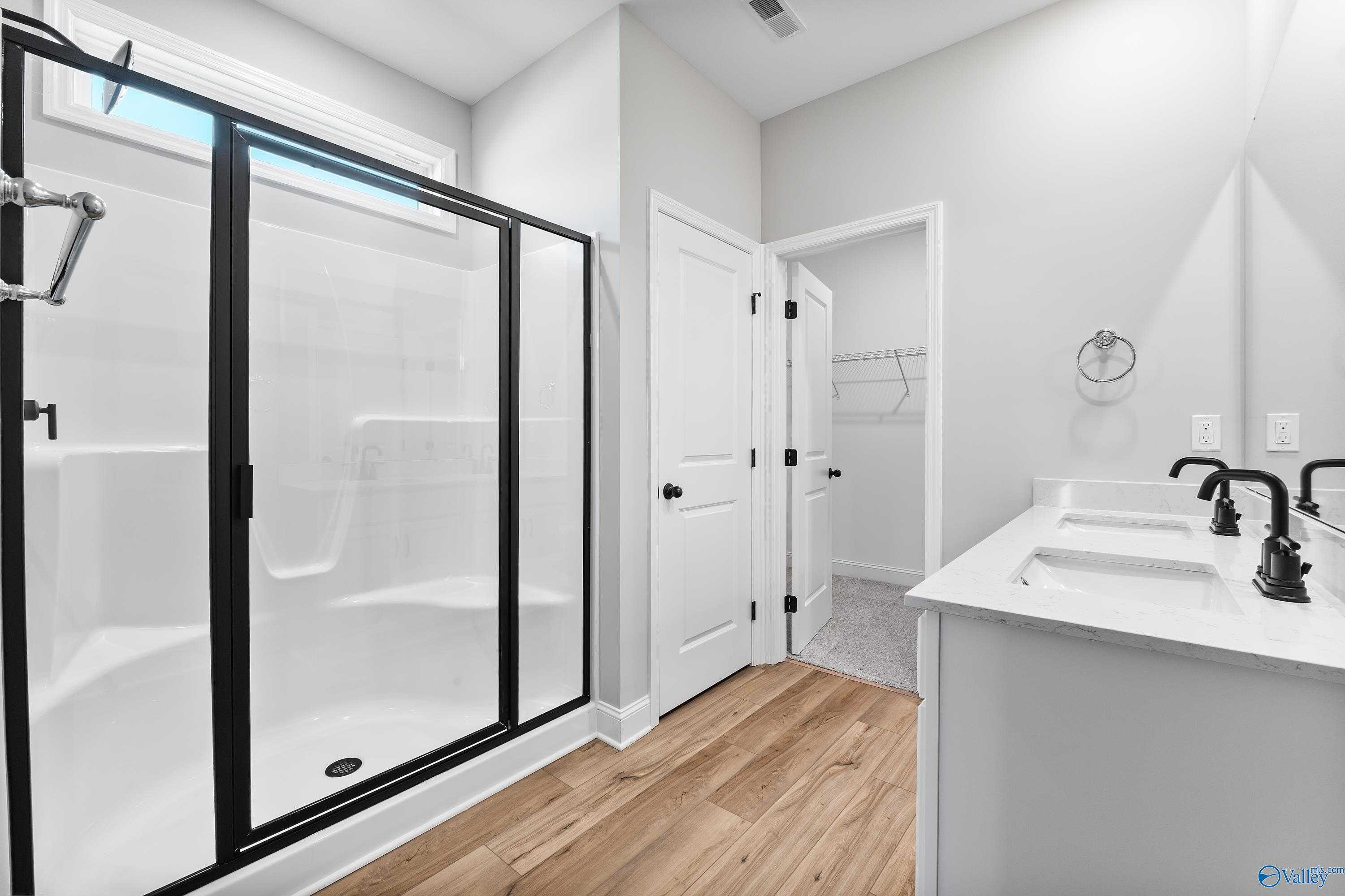 Modern master bathroom featuring frameless glass shower and double vanity in Davidson Homes The Franklin B, Hazel Green, Alabama