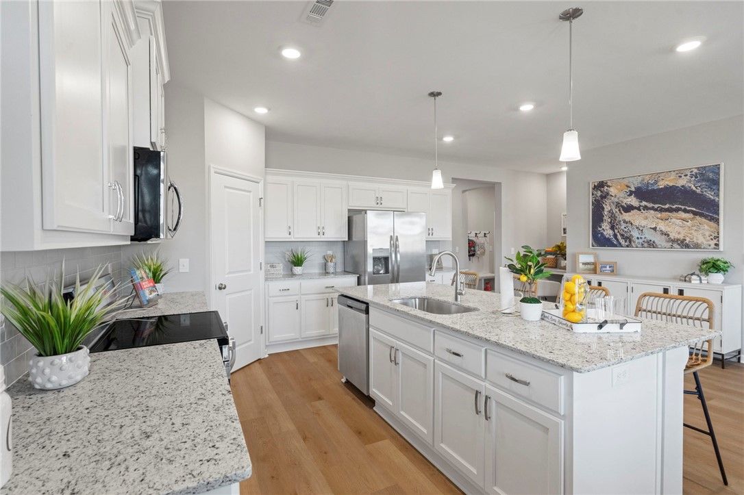 Modern white shaker kitchen with quartz island, stainless appliances, pendant lights in The Phoenix B, Opelika AL