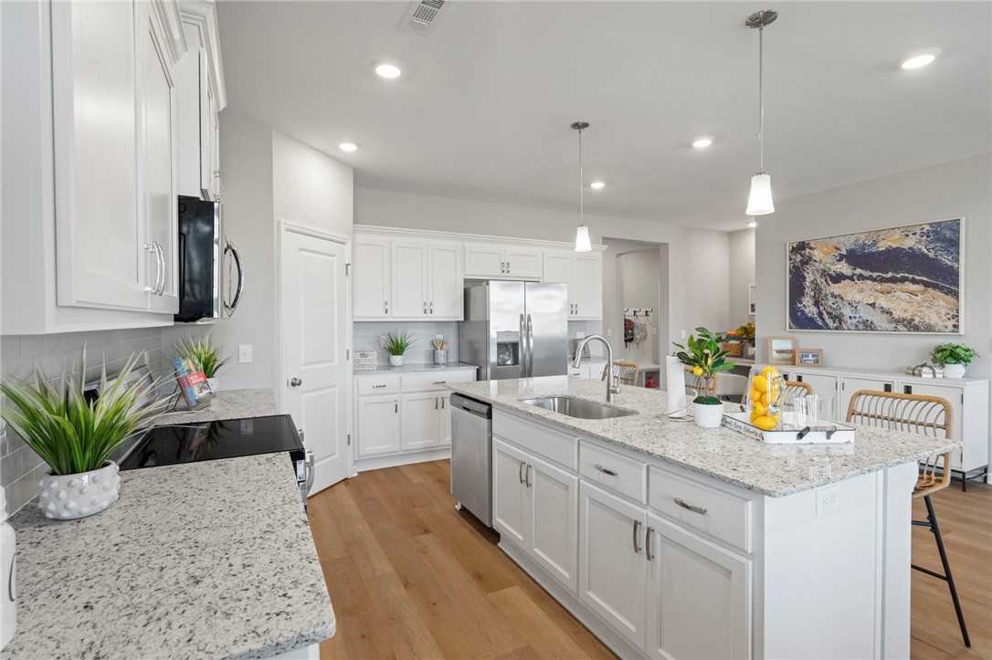 Modern white shaker kitchen with quartz island, stainless appliances, pendant lights in The Phoenix B, Opelika AL