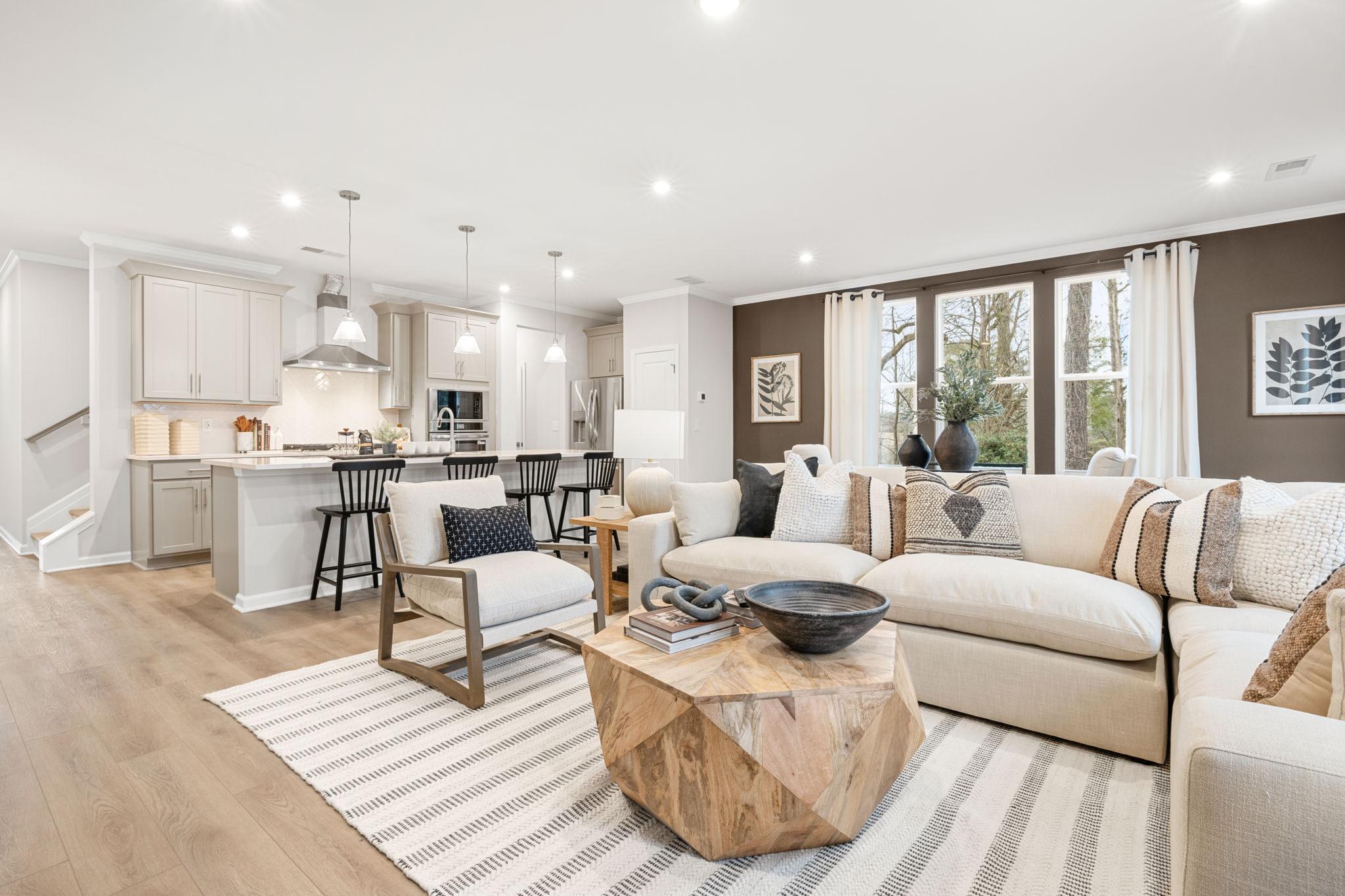 Open-concept kitchen and living room at Lake Shore in Winder GA with hardwood floors, white cabinets, island bar, and neutral sofa