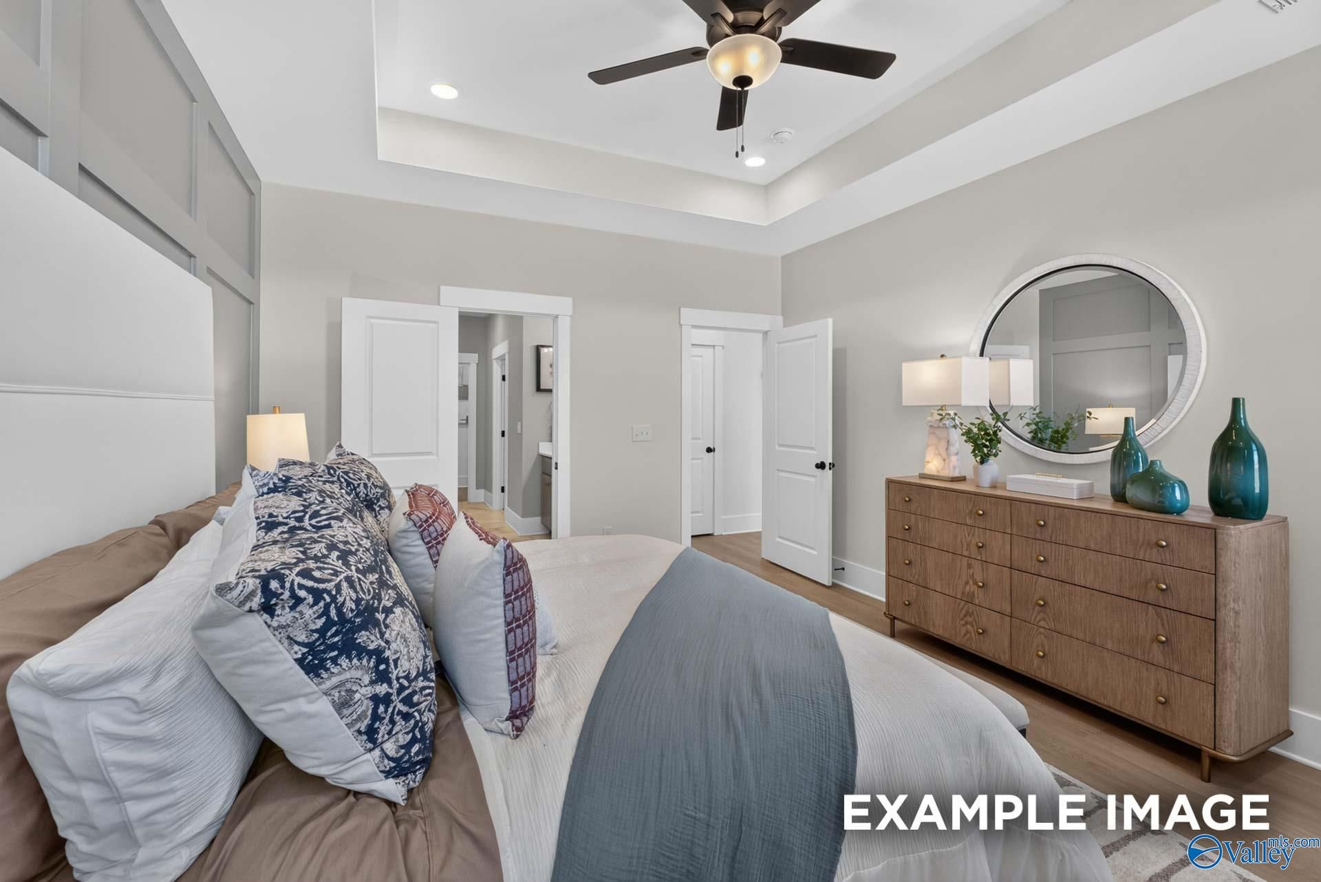 Bright primary bedroom with tray ceiling, ceiling fan, and wood dresser in Davidson Homes' The Ashport K, Forest Glen, Hazel Green, AL