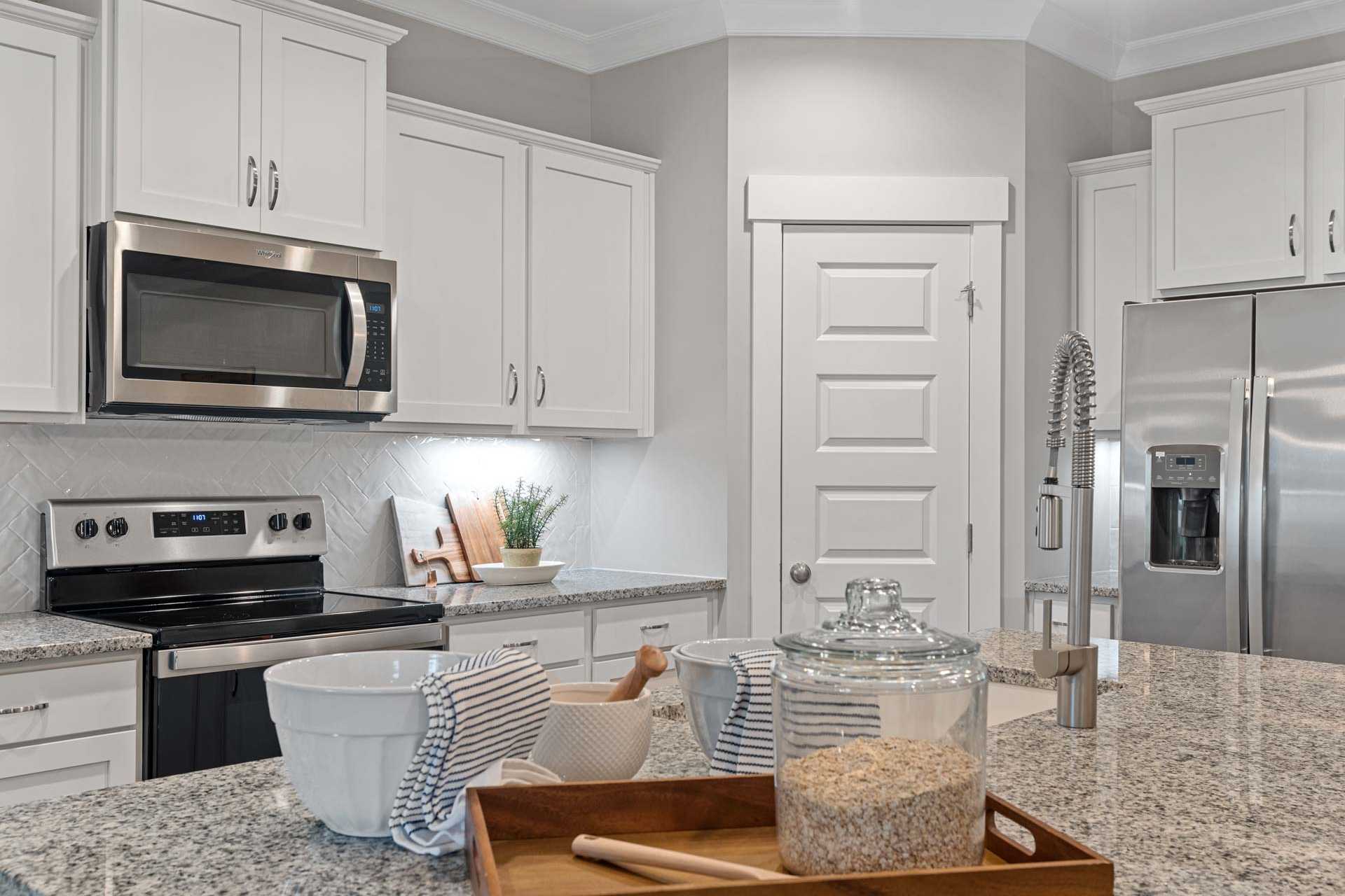Modern kitchen at Monteagle Cove in Owens Cross Roads, Alabama with white cabinets, stainless steel appliances, and granite counters