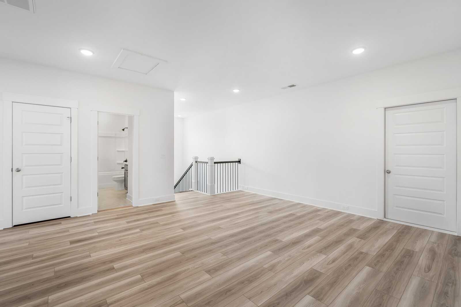 Spacious upstairs loft with light hardwood floors, white doors, guest bath, and staircase in Davidson Homes The Hathaway, Murfreesboro