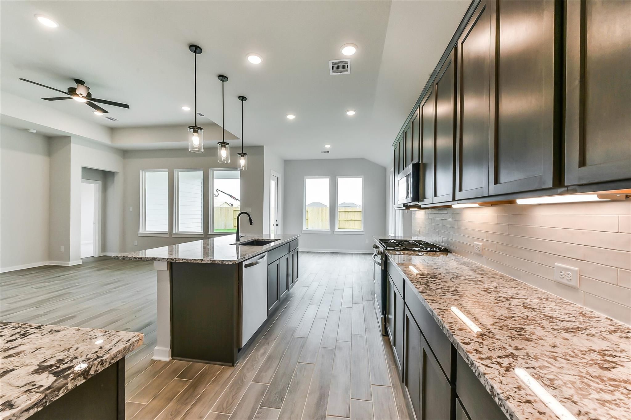 Modern open-concept kitchen with granite island, dark cabinets, stainless appliances in Davidson Homes Sequoia C, Crosby Texas