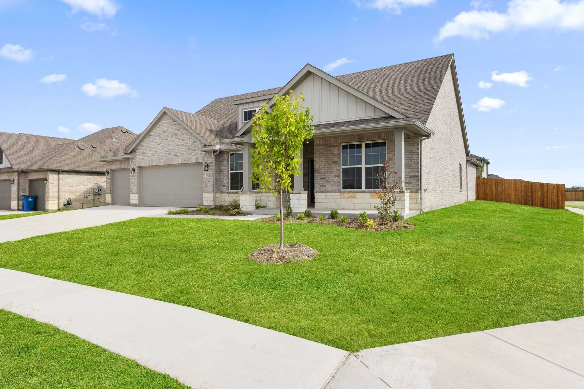 Brick single-story 4-bedroom home with 3-car garage, young tree, and lush green lawn in Waverly Estates, Josephine, Texas by Davidson Homes The Harrison D