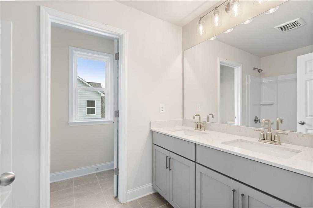 Modern double vanity with gray cabinets, white quartz counters, and glass shower in Davidson Homes The Willow B, Hoschton, GA