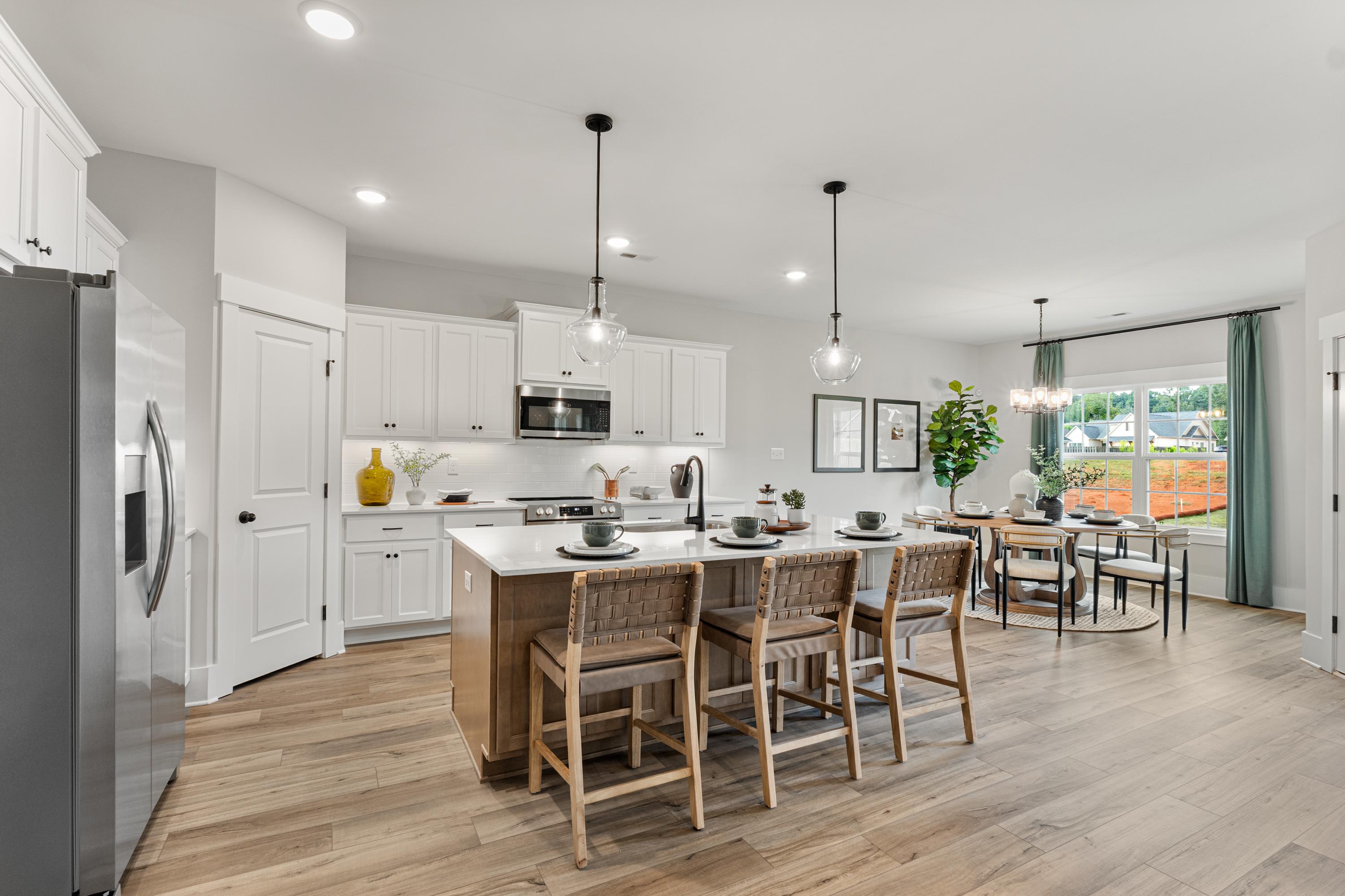 Spacious white kitchen at River Road Estates in Decatur Alabama with island bar stools, hardwood floors, pendant lights