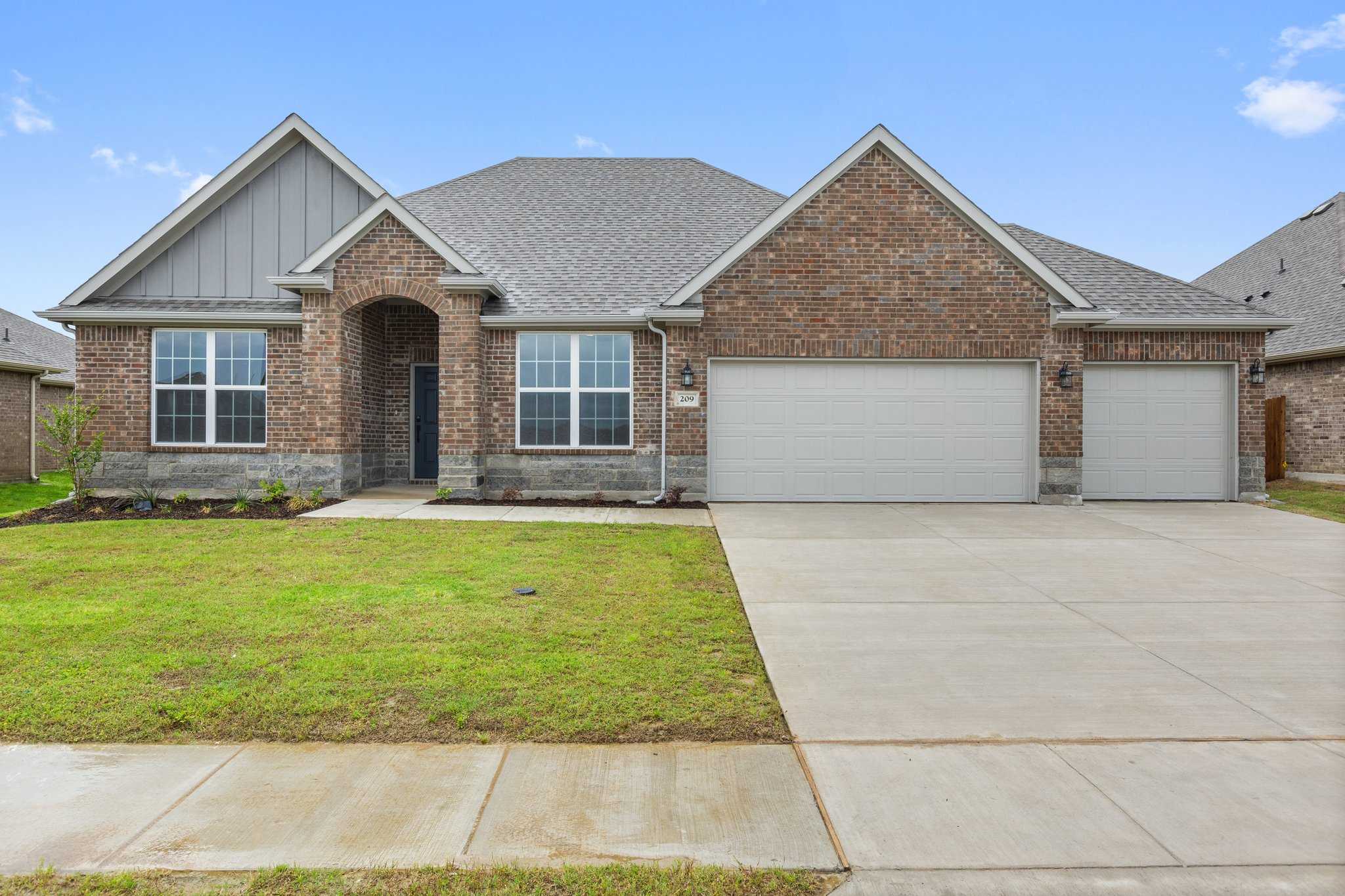 Modern single-story The Harrison D exterior with brick and siding, 3-car garage, arched entry, and lush green lawn