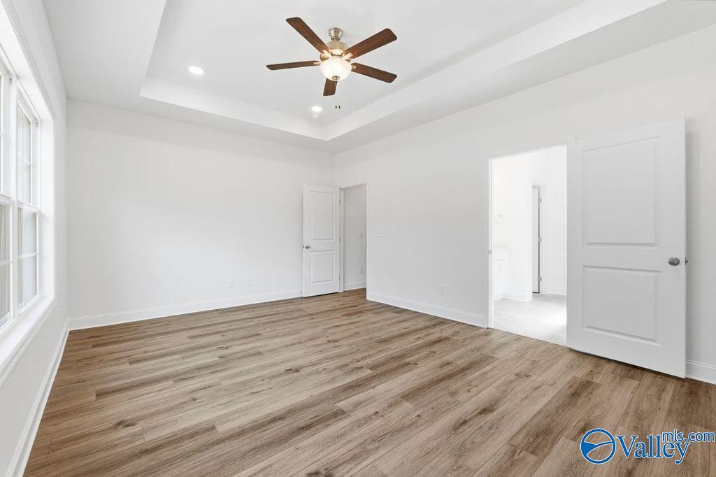 Bright master bedroom with tray ceiling, ceiling fan, hardwood floors, and en-suite bath in Davidson Homes The Montgomery, Hartselle Alabama