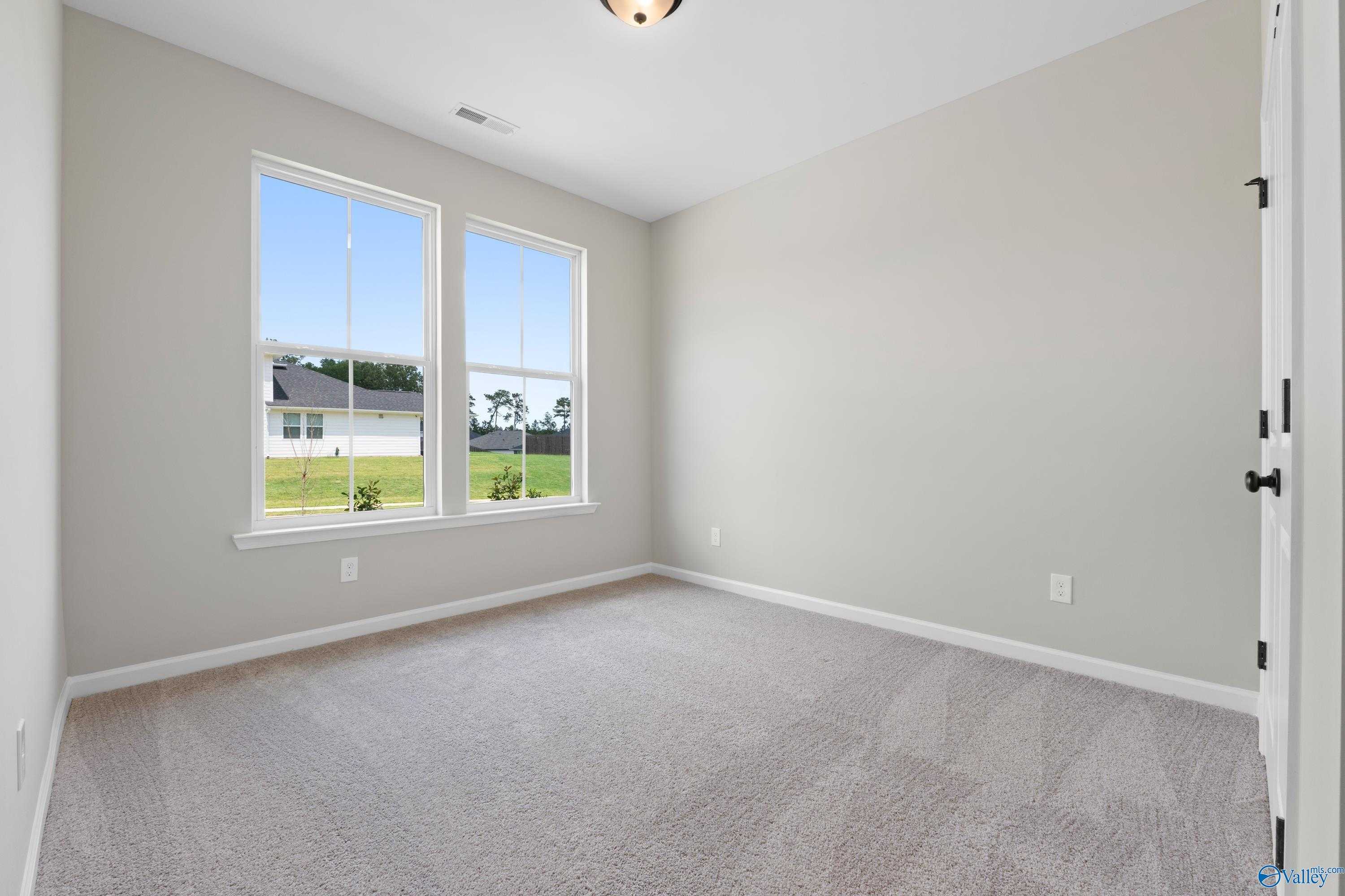 Bright empty bedroom with large windows and green yard view in Evermore Homes The Nantucket, Madison, Alabama
