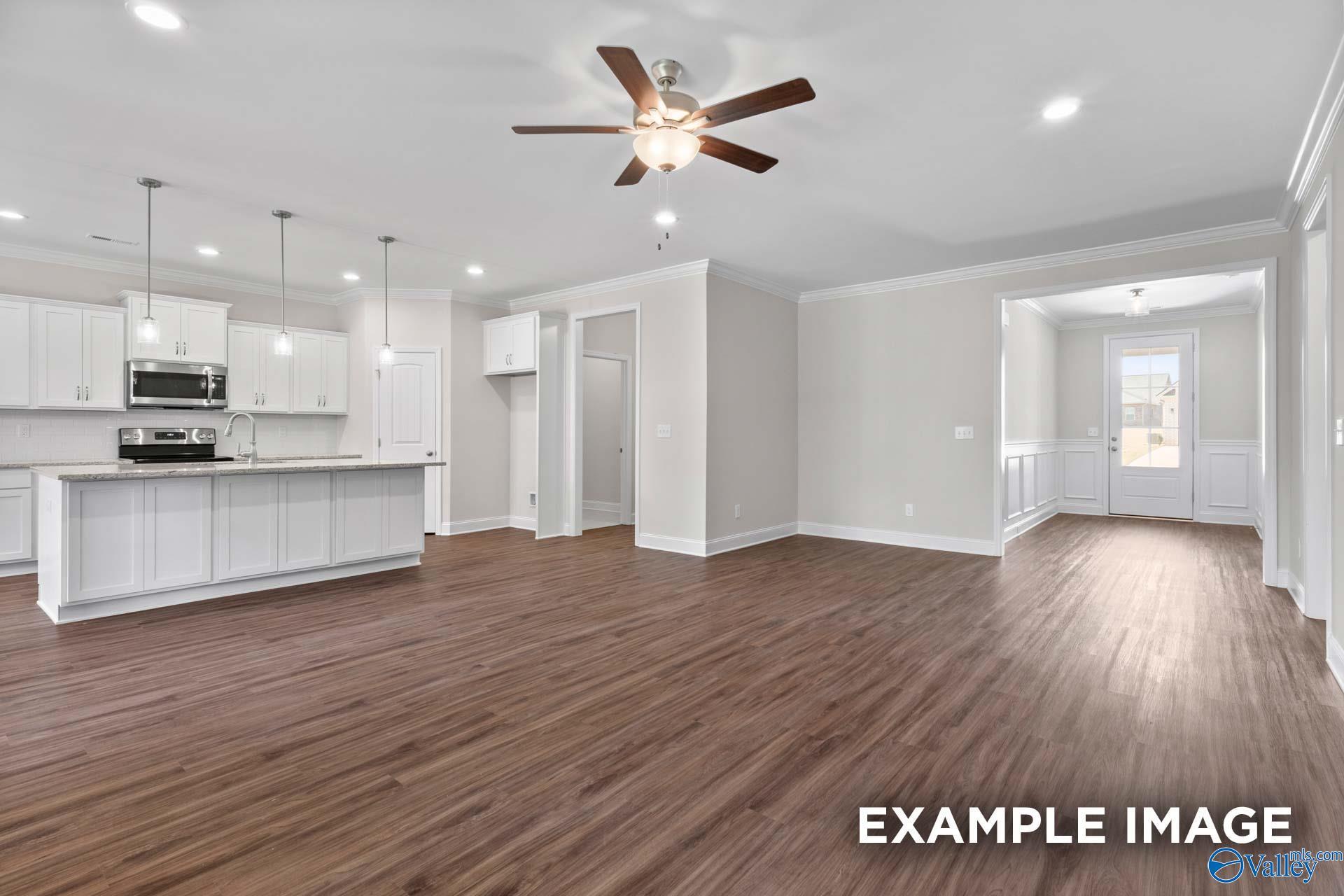 Modern open-concept kitchen with white cabinets, large island, and ceiling fan in The Montgomery C by Davidson Homes, Harvest, Alabama