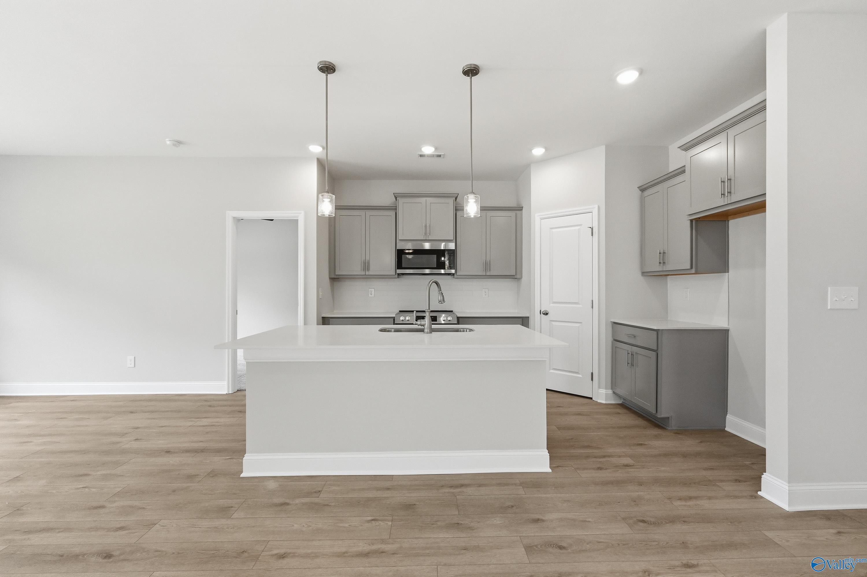 Modern white kitchen island with sink, stainless oven, and recessed lighting in The Franklin floor plan by Davidson Homes, Meridianville, Alabama