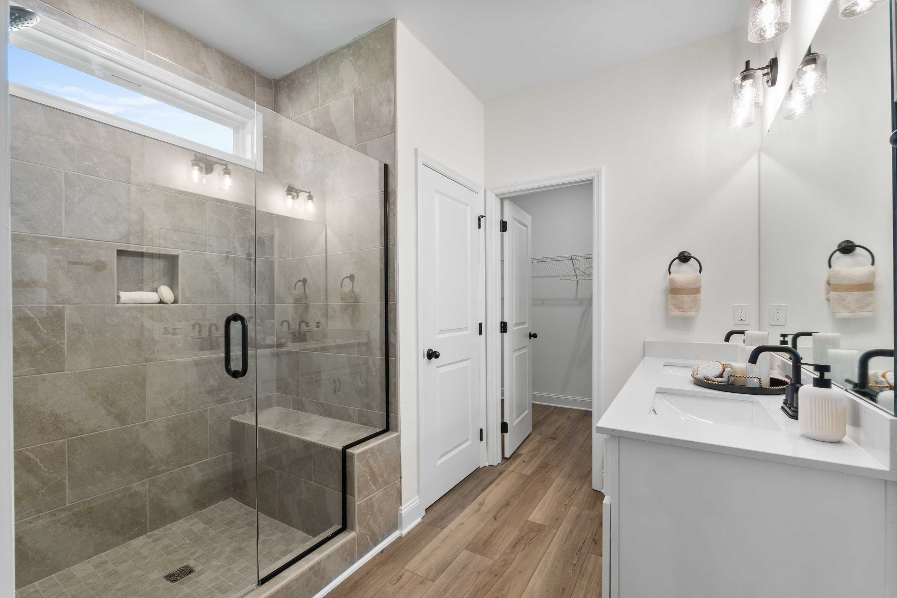 Spacious primary bathroom in Lynn Meadows Meridianville AL with glass-enclosed tiled shower double vanity and hardwood floors