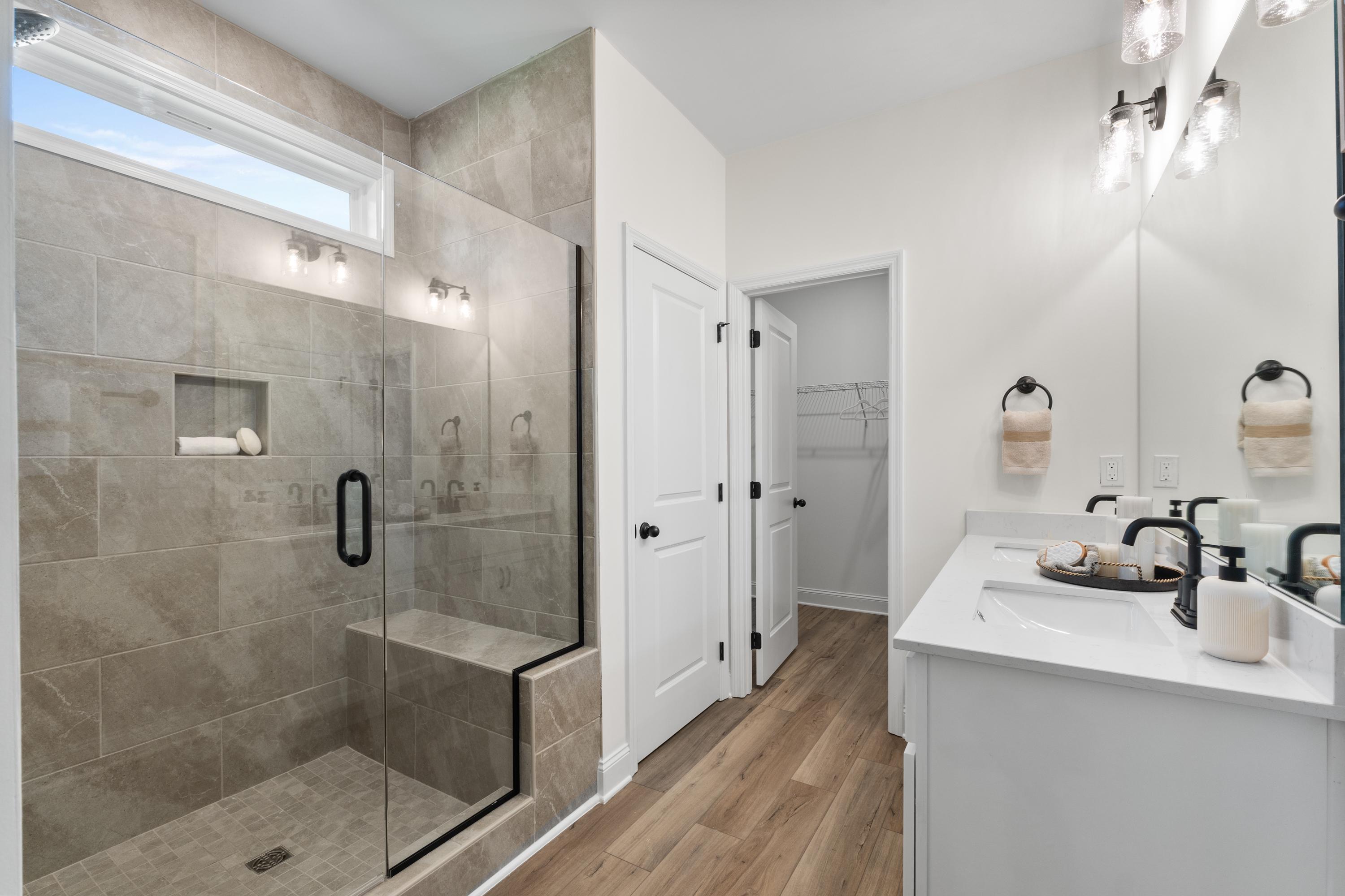 Spacious primary bathroom in Lynn Meadows Meridianville AL with glass-enclosed tiled shower double vanity and hardwood floors