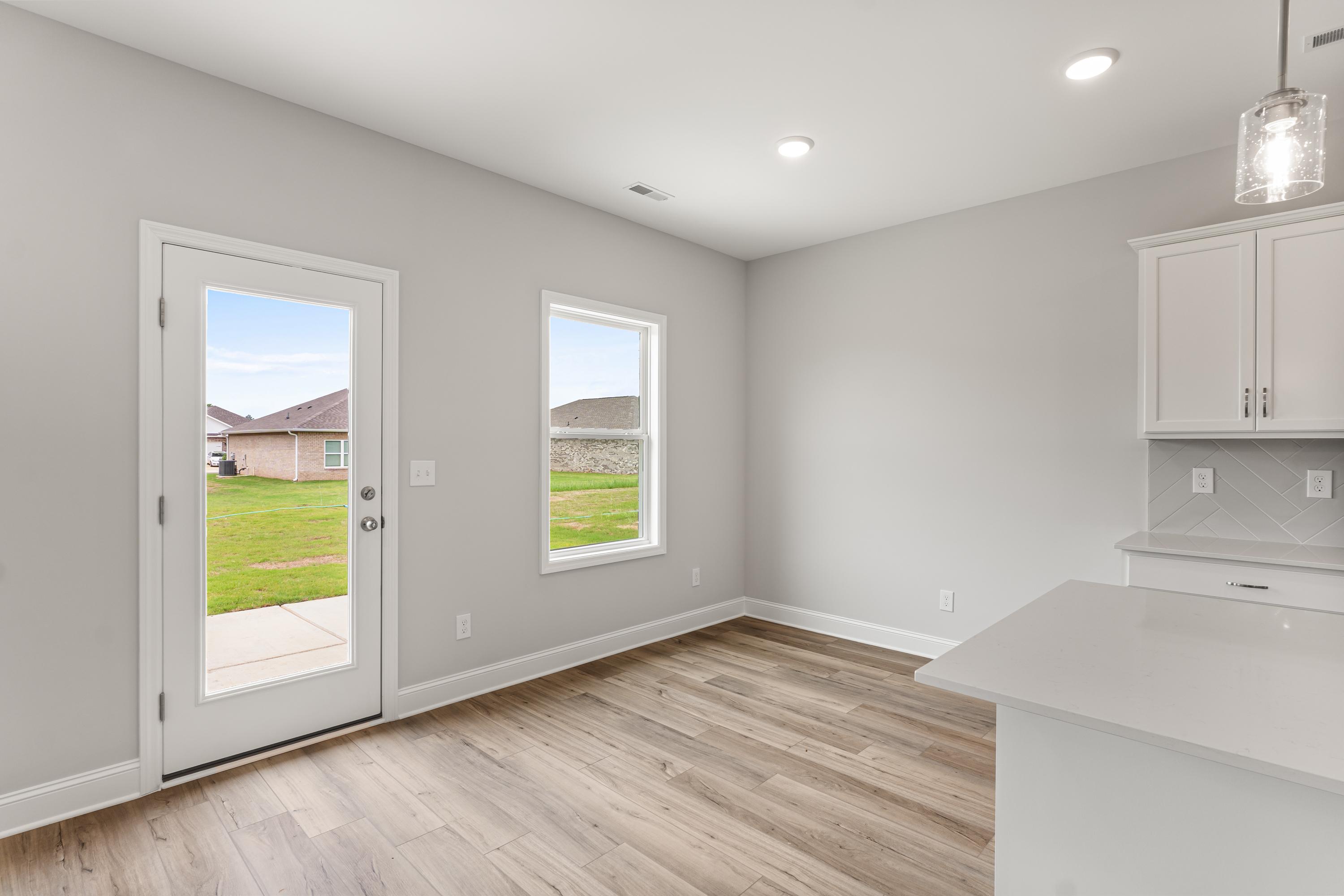 Spacious kitchen in The Butler home by Davidson Homes with white cabinets, quartz counters, and backyard view via glass door
