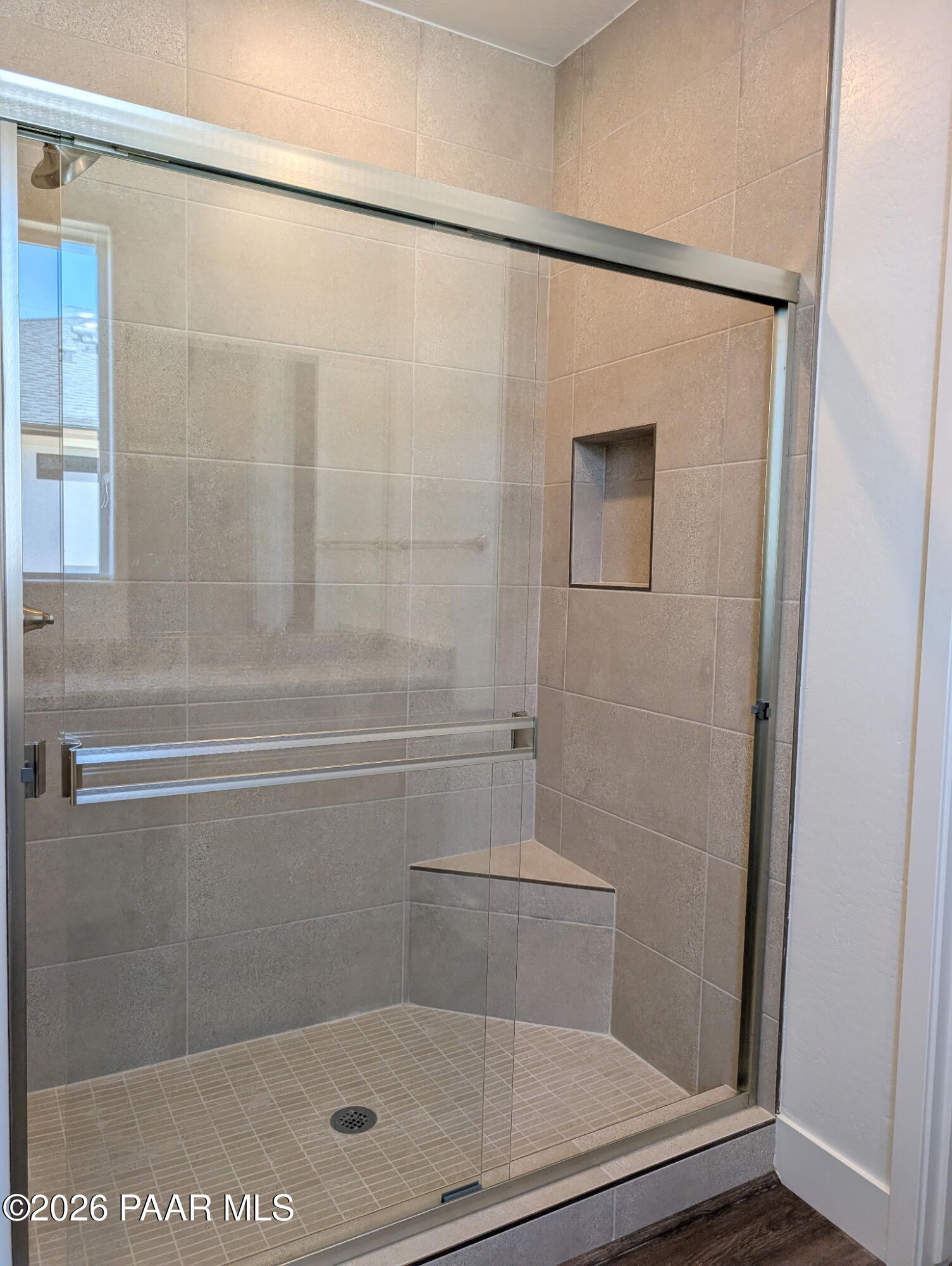 Tiled walk-in shower with built-in bench and glass enclosure in The Frontier II F home, South Ranch, Prescott, Arizona.