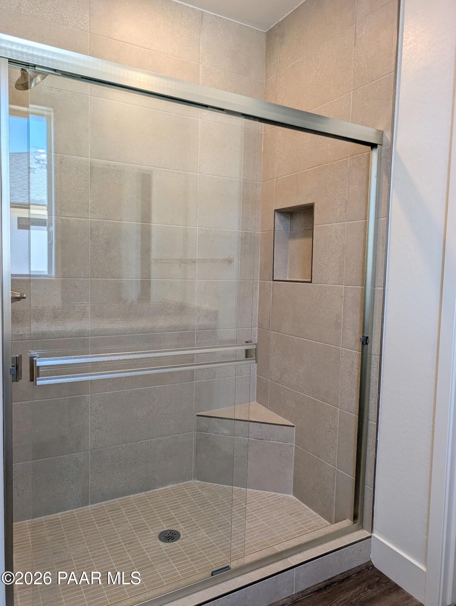 Tiled walk-in shower with built-in bench and glass enclosure in The Frontier II F home, South Ranch, Prescott, Arizona.