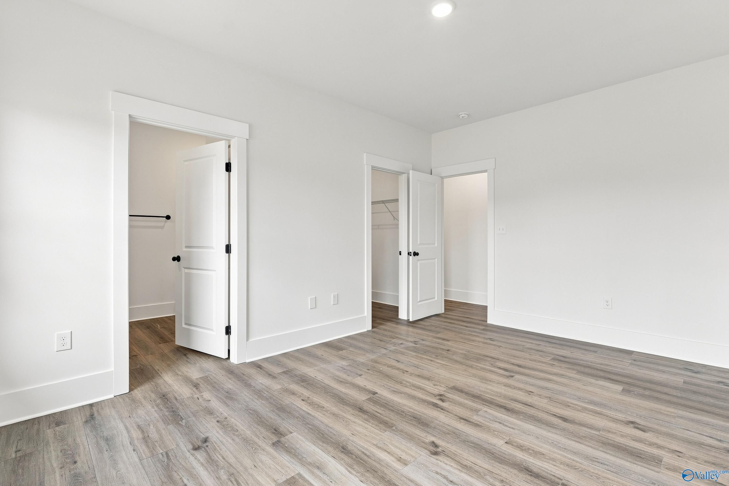 Spacious primary bedroom with luxury vinyl plank flooring and walk-in closet in The Valencia floor plan, Riverton Preserve, Huntsville
