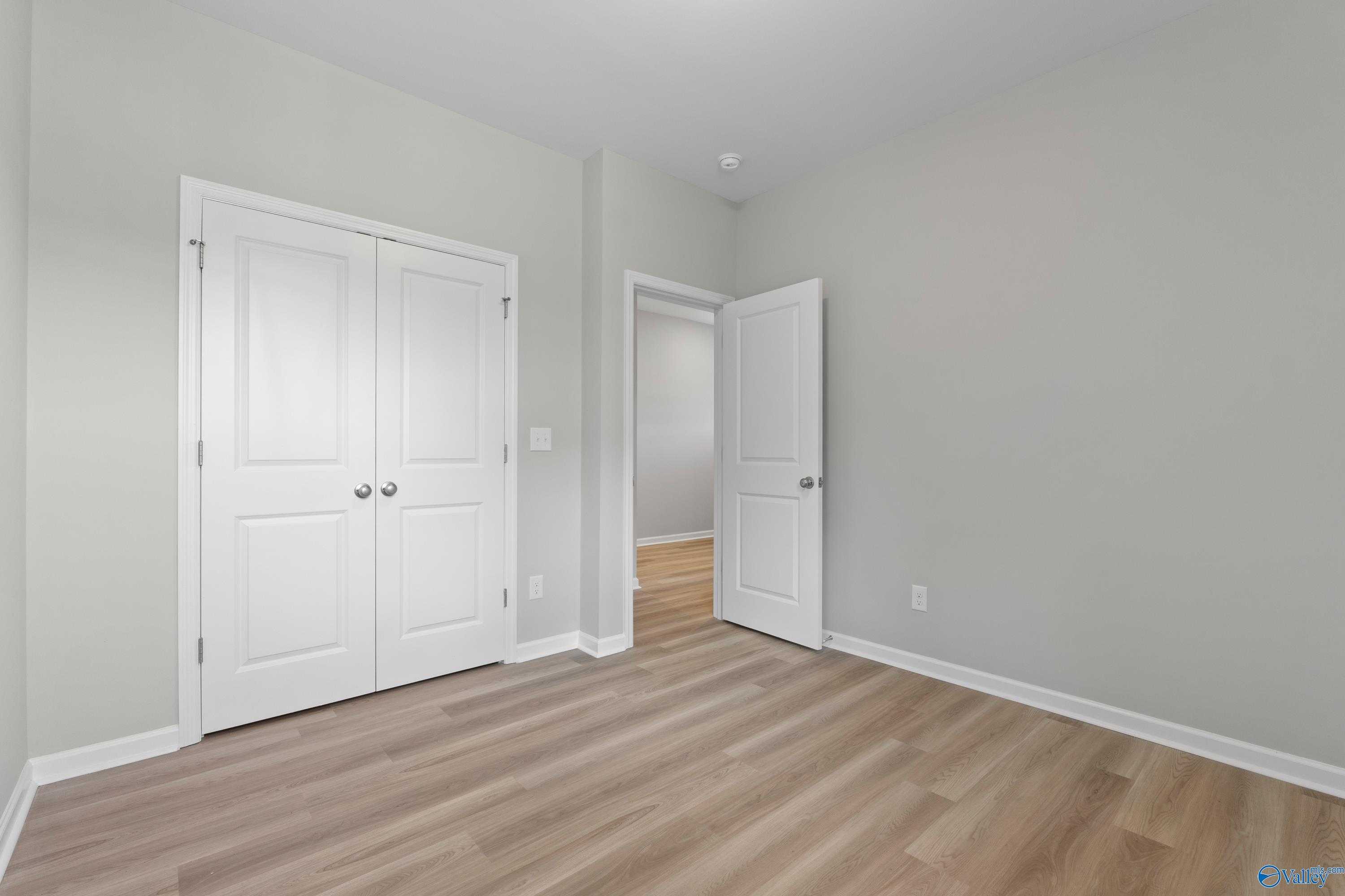 Bright secondary bedroom with gray walls, white double closet doors, and light wood floors in Davidson Homes The Polaris, Fayetteville TN
