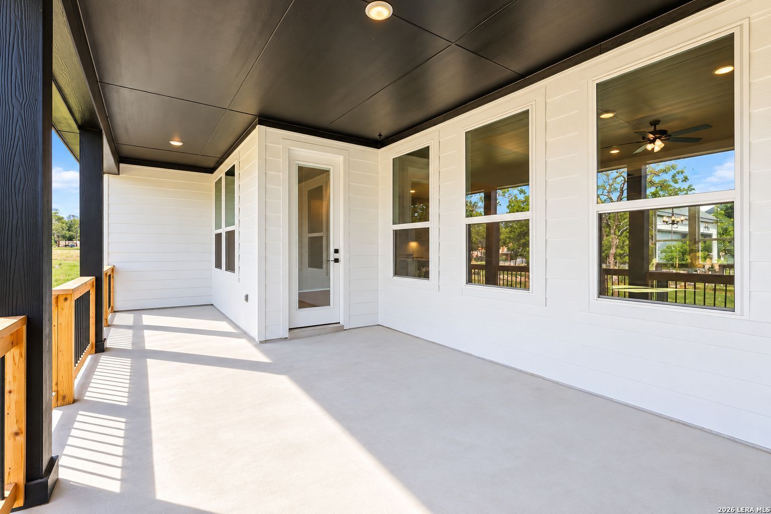 Covered concrete patio with black ceiling and wood railings on Davidson Homes The Oxford F in Potranco Oaks, Castroville, Texas