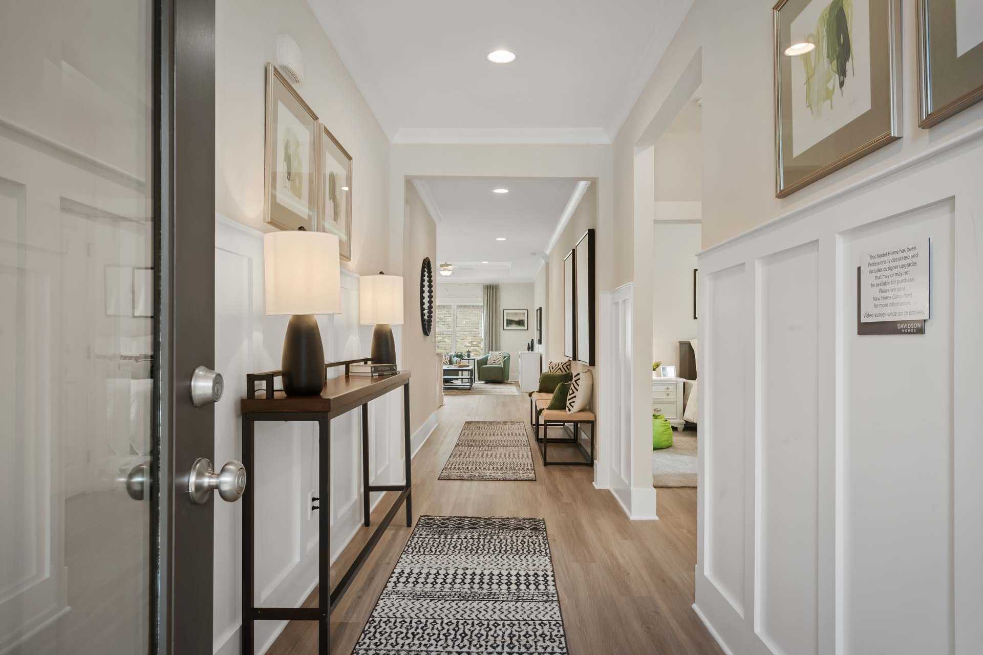 Spacious foyer hallway in Durham Farms home, Harvest Alabama with hardwood floors, wainscoting, console table and runner rug