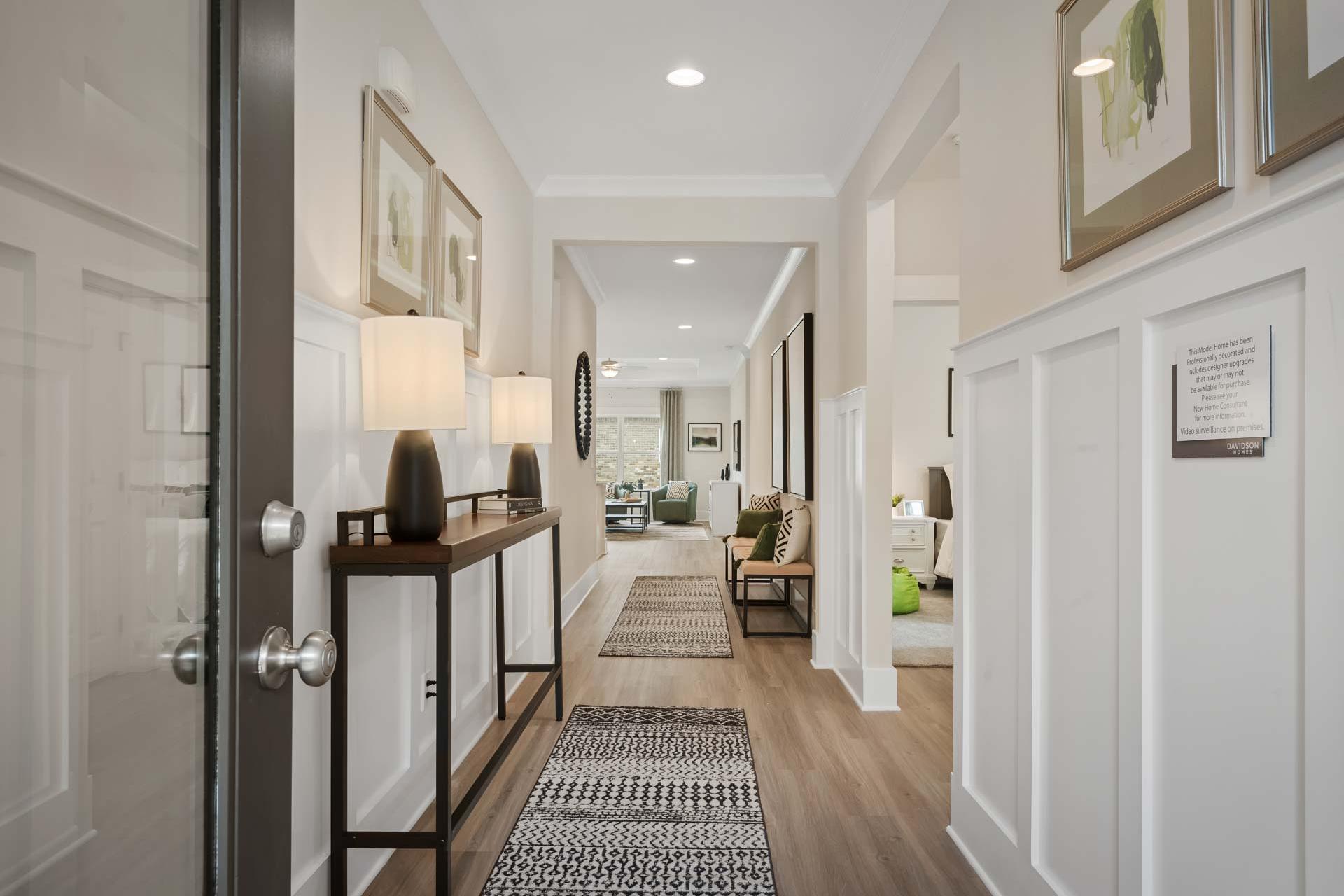 Spacious foyer hallway in Durham Farms home, Harvest Alabama with hardwood floors, wainscoting, console table and runner rug