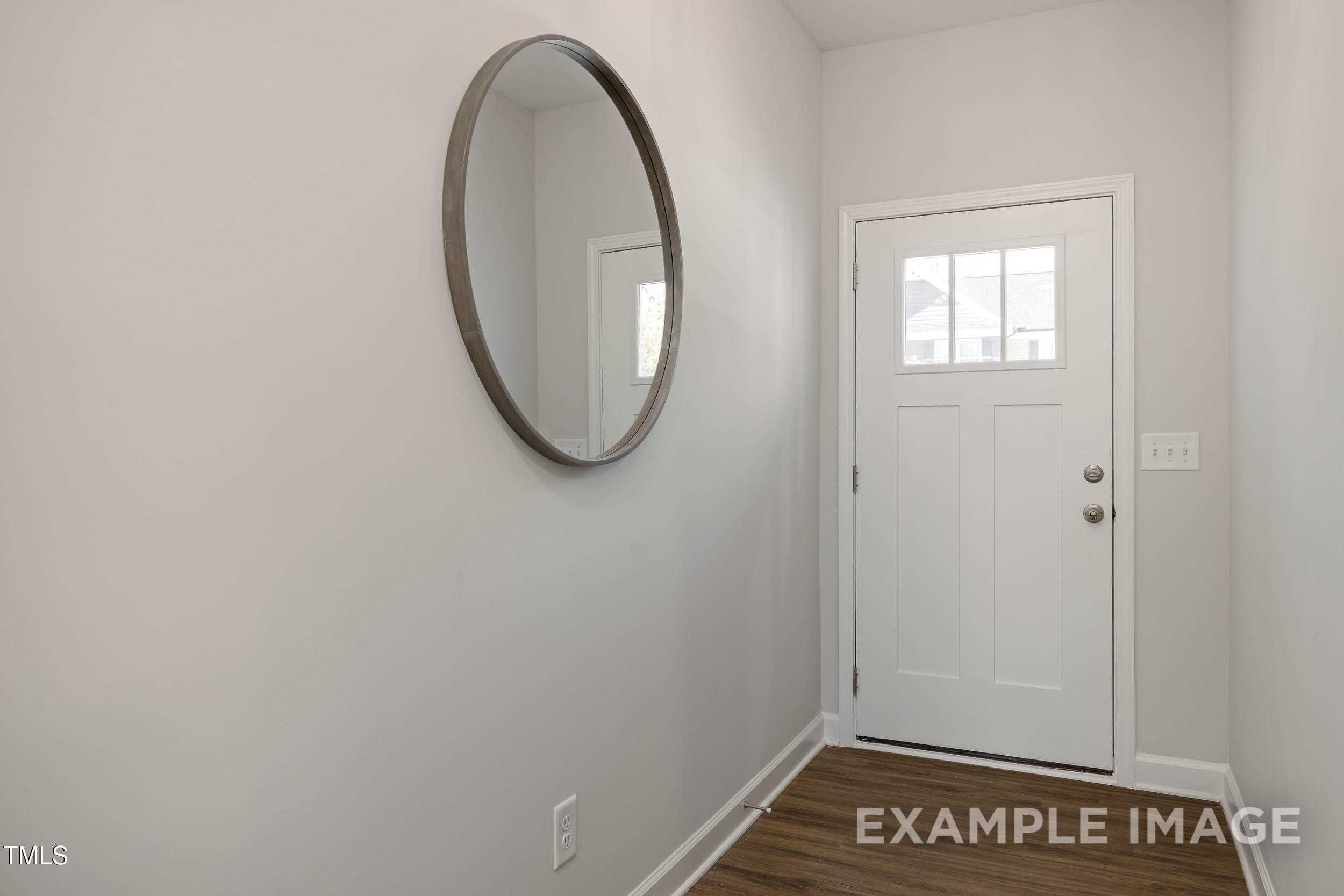 Modern entryway with large round mirror and white glass-paneled door in Davidson Homes The Graham, Fuquay-Varina, NC